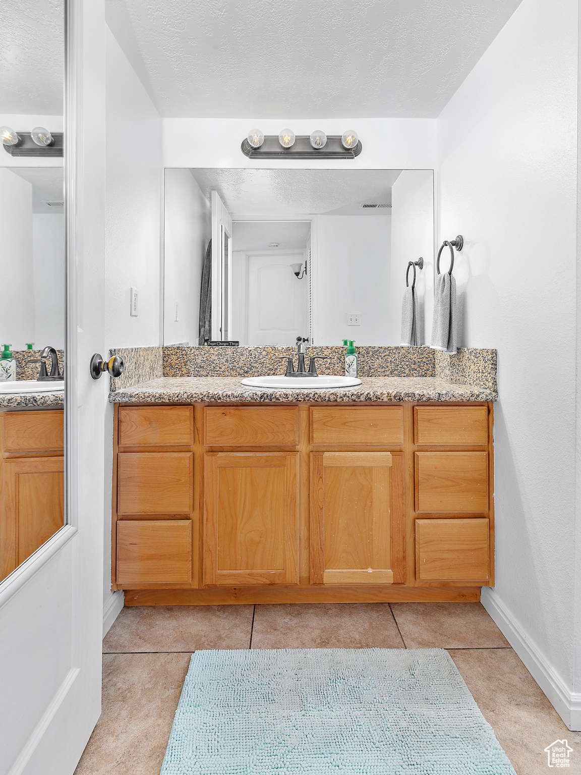 Bathroom featuring tile patterned flooring, a textured ceiling, and vanity