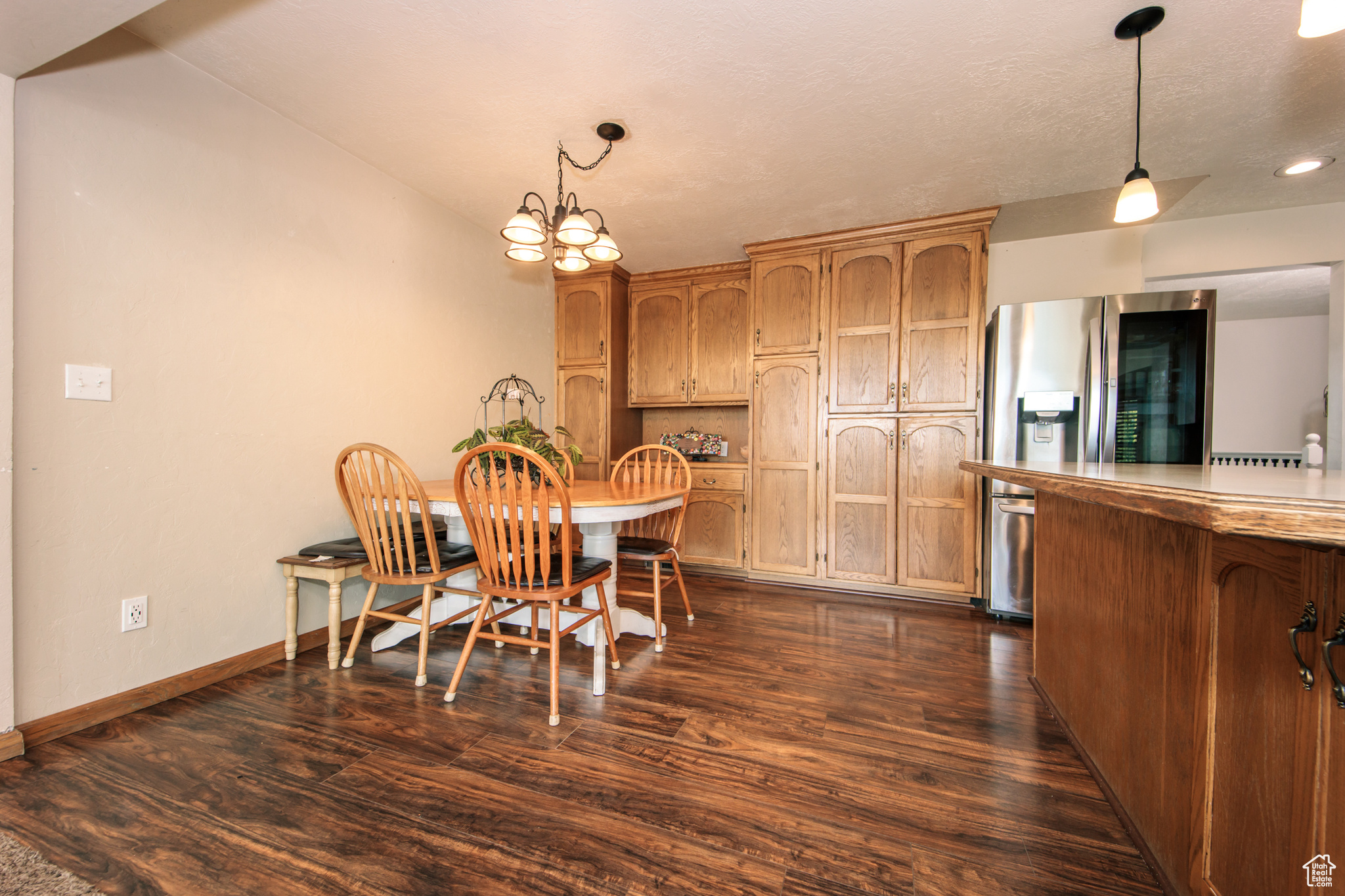 Dining area with a textured ceiling, dark hardwood / wood-style flooring, and a notable chandelier