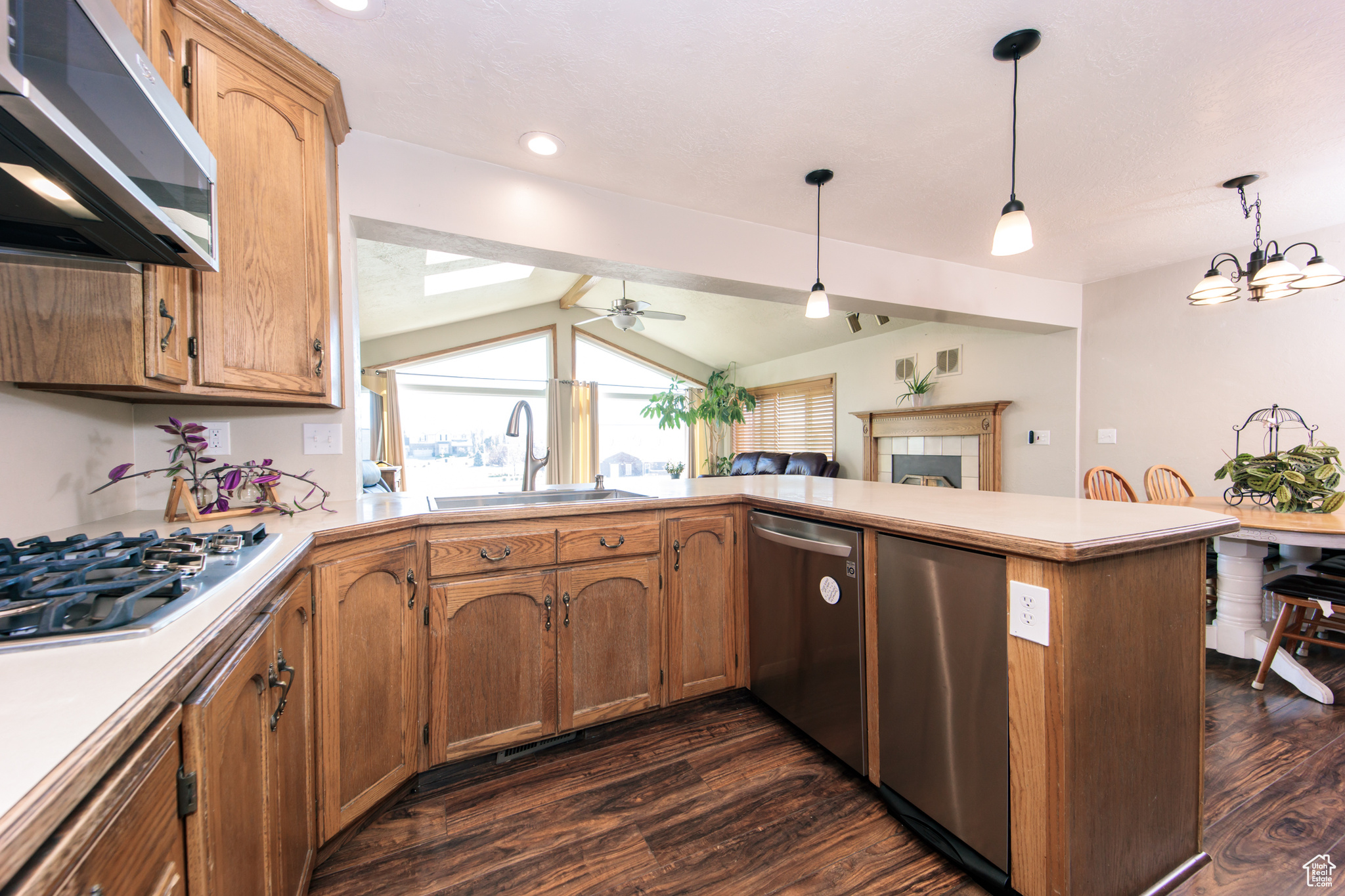 Kitchen with pendant lighting, sink, kitchen peninsula, stainless steel appliances, and dark hardwood / wood-style flooring