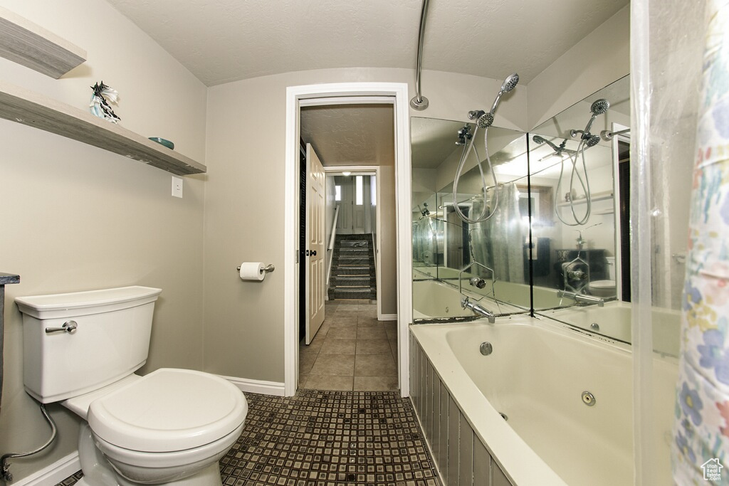 Bathroom featuring shower / bath combo, vaulted ceiling, toilet, and tile patterned floors