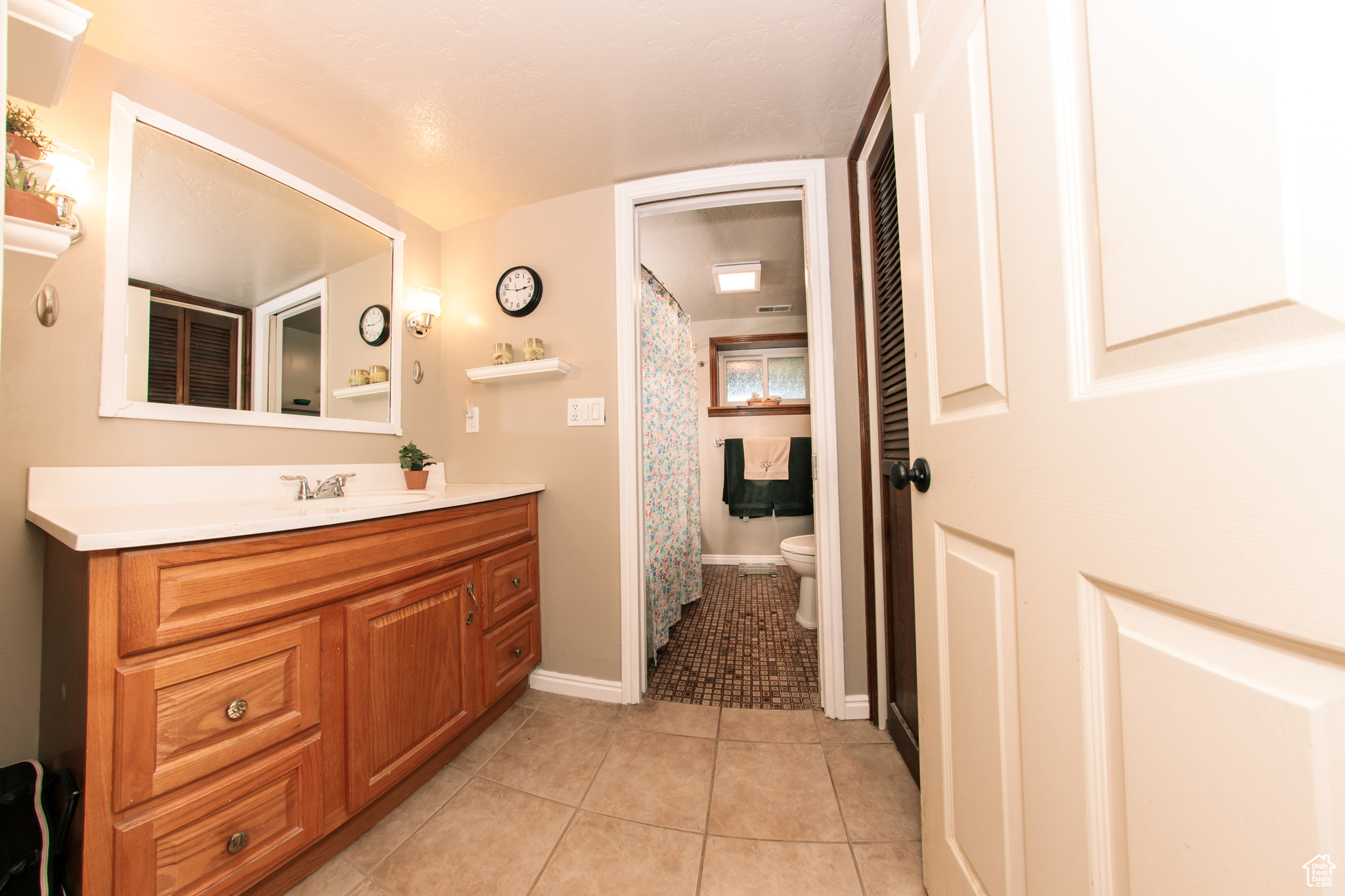 Bathroom with a shower with curtain, vanity, toilet, and tile patterned floors