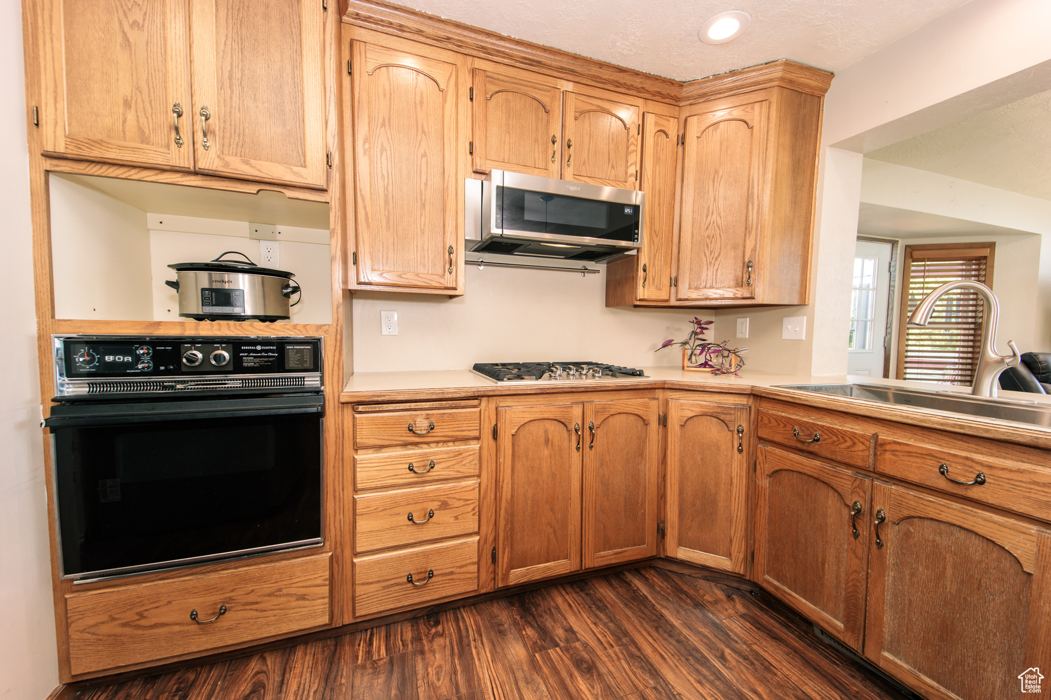 Kitchen with appliances with stainless steel finishes, sink, and dark hardwood / wood-style floors