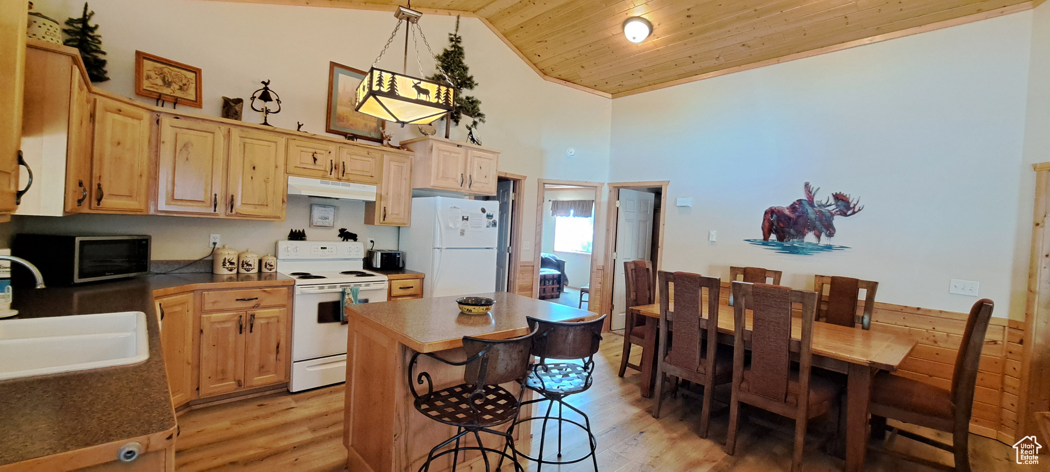 Kitchen featuring wood ceiling, pendant lighting, sink, white appliances, and light brown cabinetry