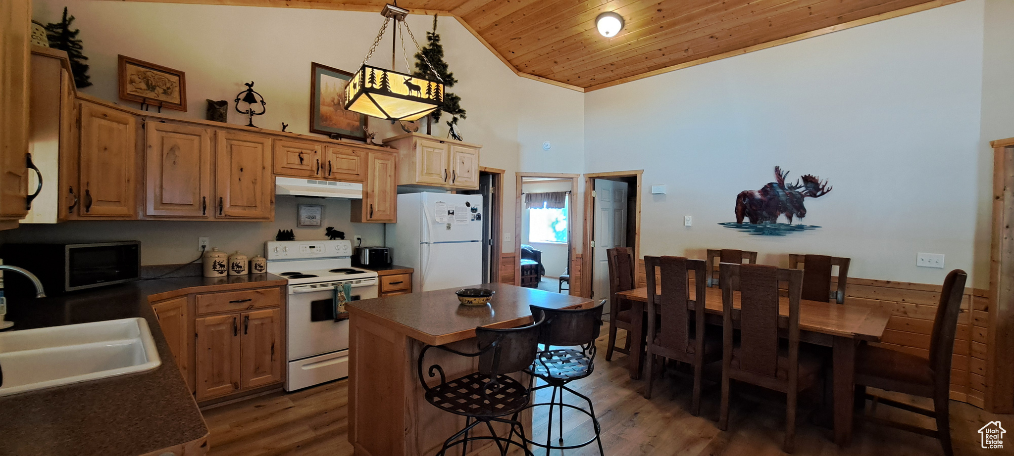 Kitchen with a center island, sink, hanging light fixtures, white appliances, and wooden ceiling