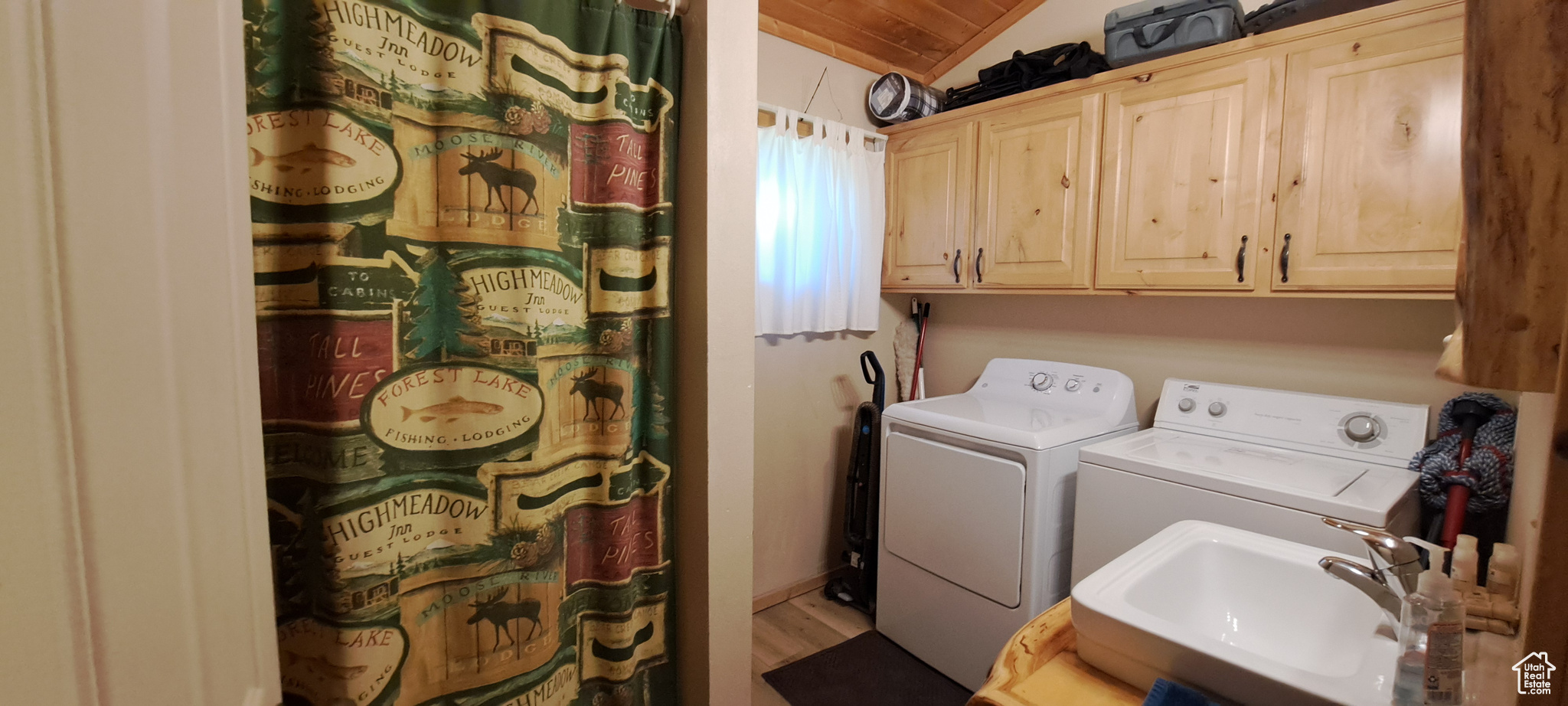 Clothes washing area with hardwood / wood-style flooring, washing machine and dryer, sink, and cabinets