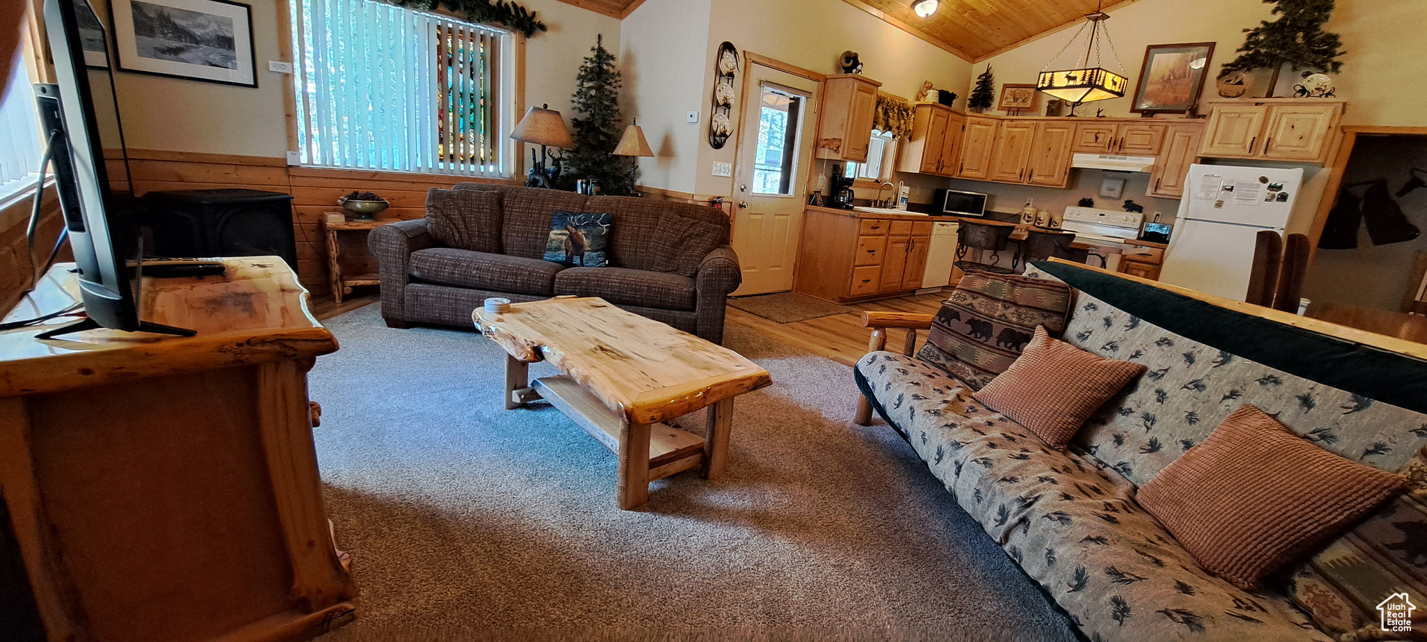 Carpeted living room with wooden walls and vaulted ceiling