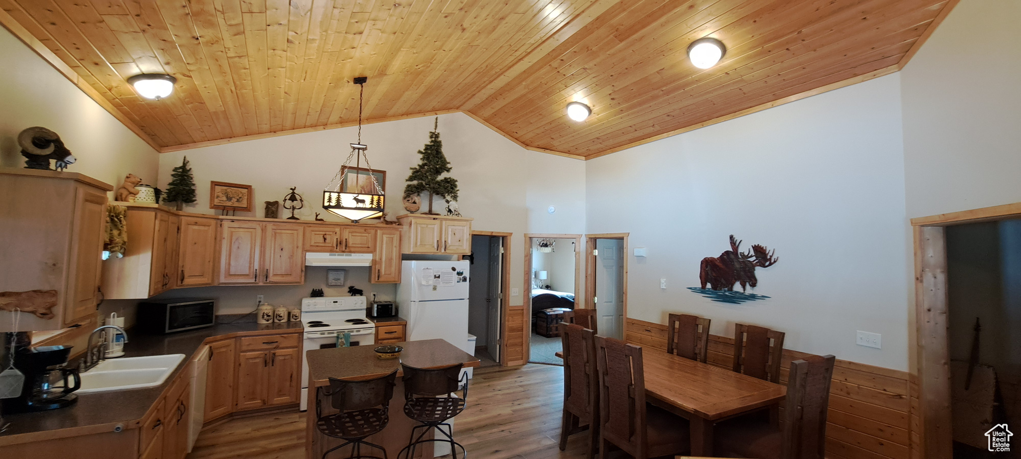 Kitchen with wood ceiling, sink, white appliances, and a center island