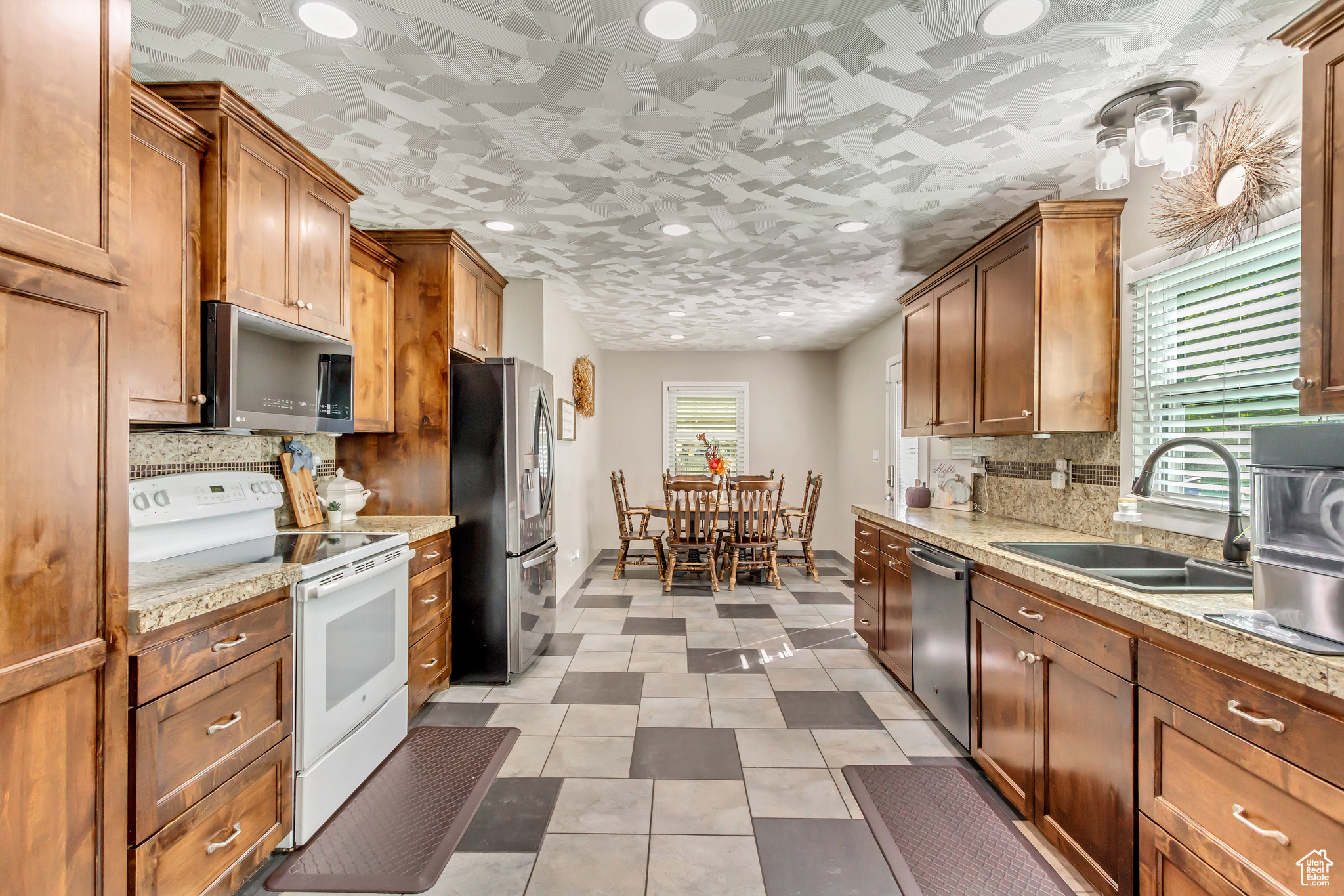 Kitchen featuring stainless steel appliances, tasteful backsplash, light tile patterned floors, and sink