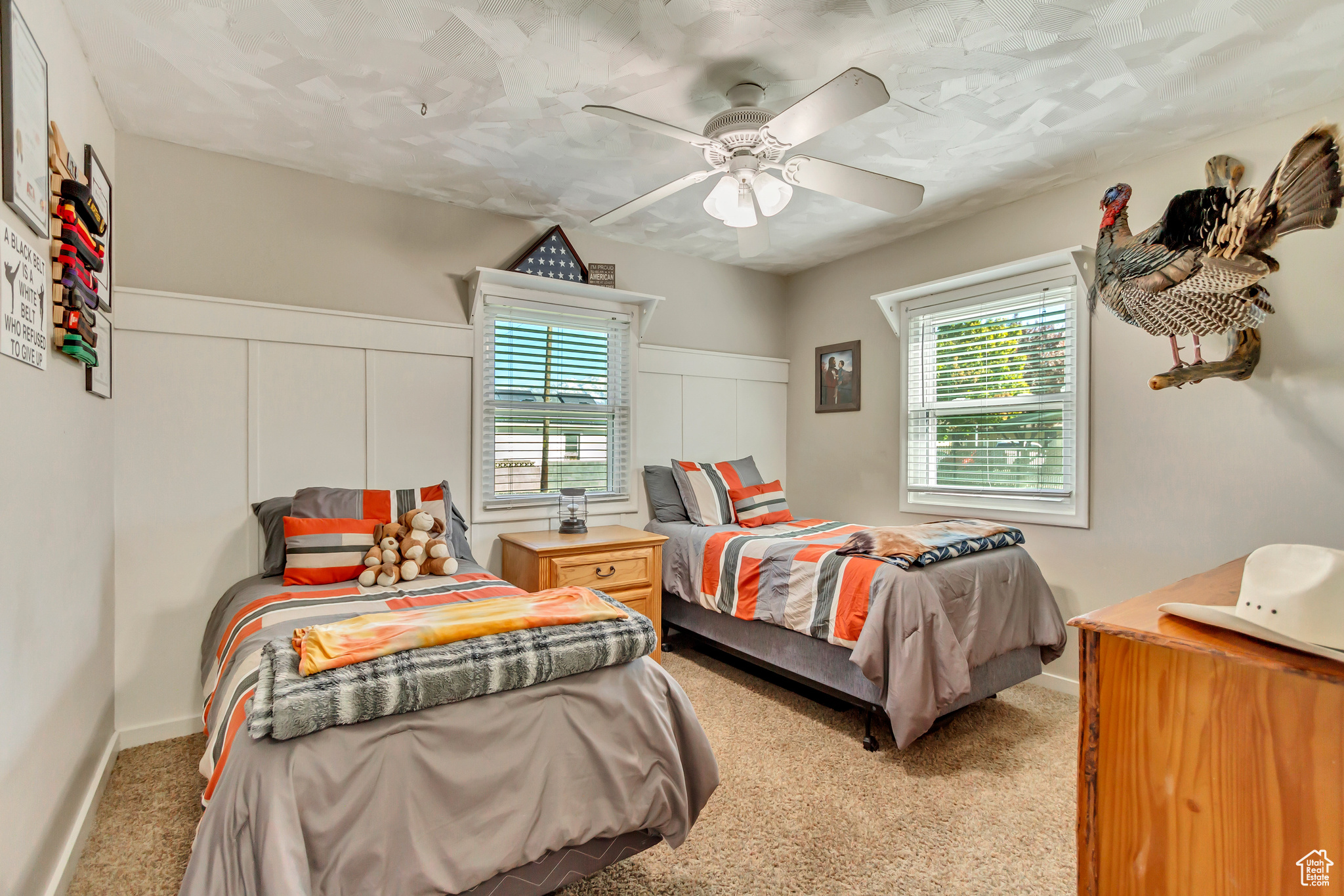 Carpeted bedroom featuring multiple windows and ceiling fan