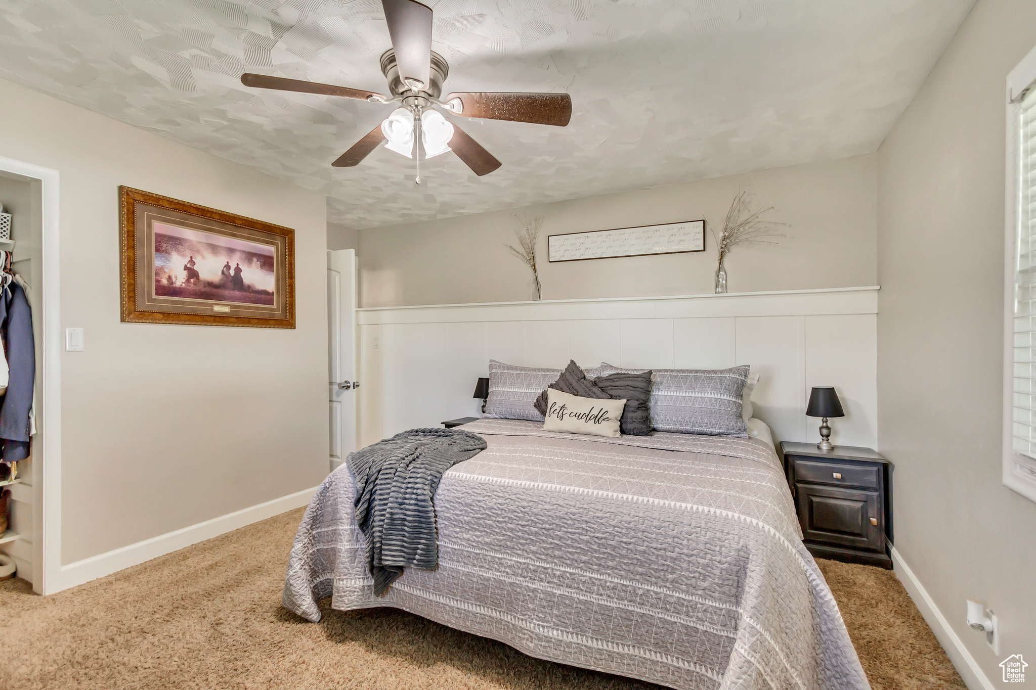 Carpeted bedroom featuring ceiling fan and a textured ceiling