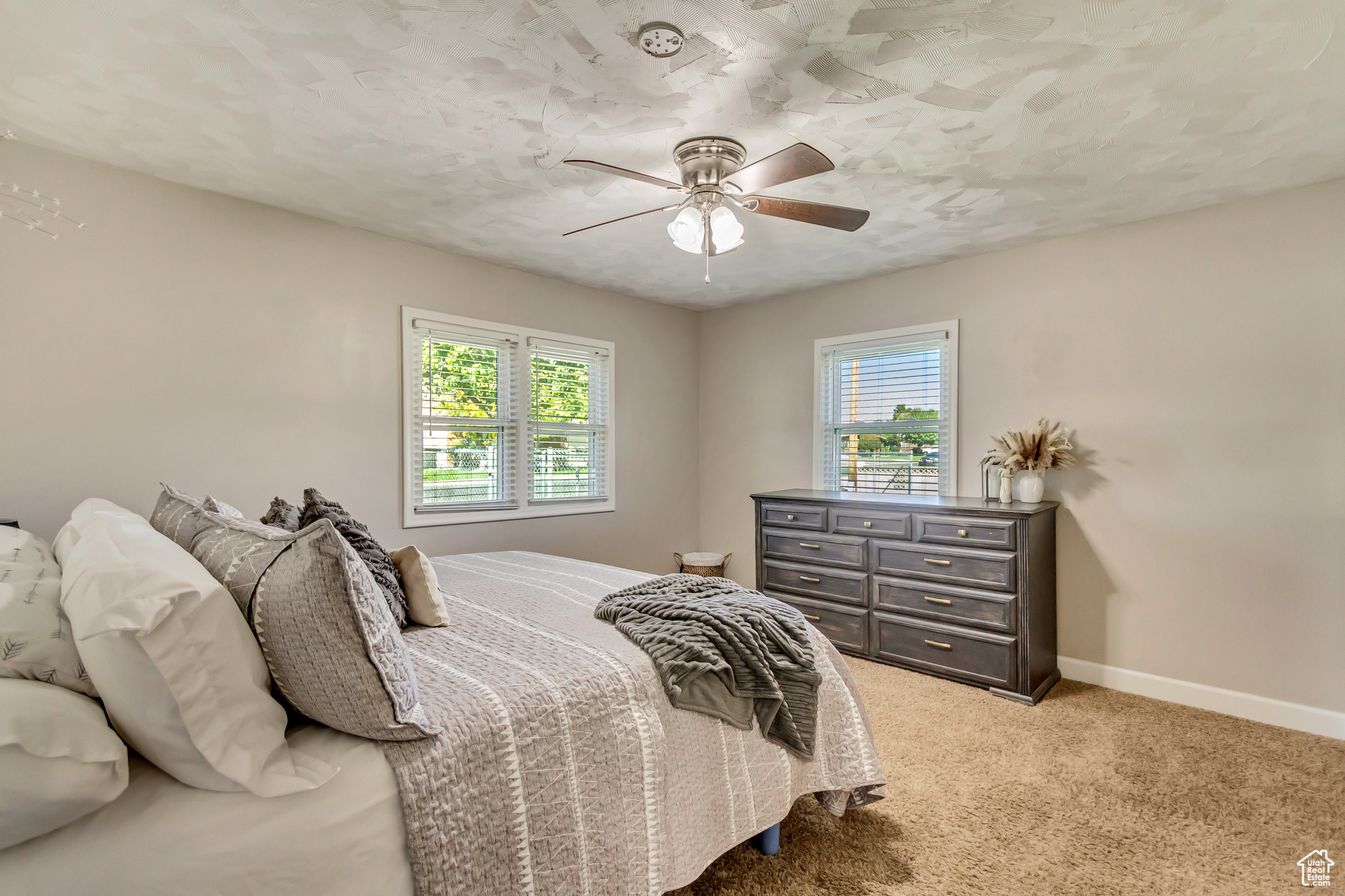 Carpeted bedroom featuring multiple windows and ceiling fan