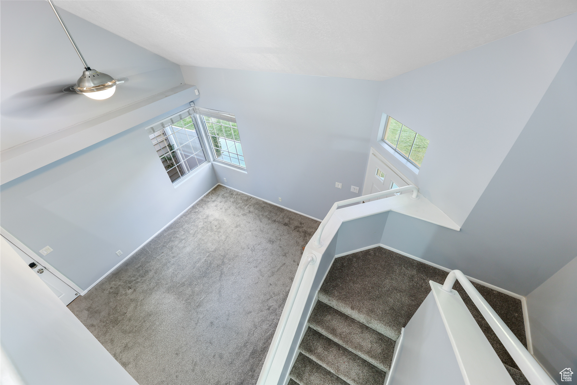 Staircase with carpet flooring, vaulted ceiling, and a healthy amount of sunlight