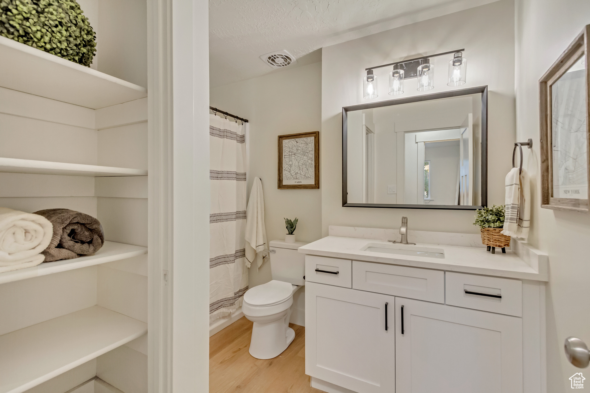 Bathroom with vanity, curtained shower, a textured ceiling, hardwood / wood-style flooring, and toilet