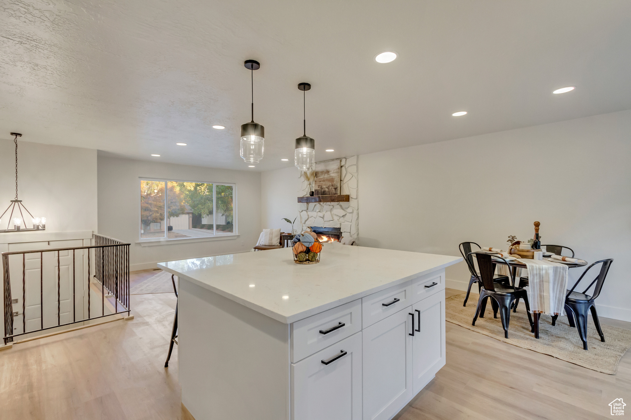 Kitchen with light hardwood / wood-style floors, a stone fireplace, pendant lighting, and white cabinets