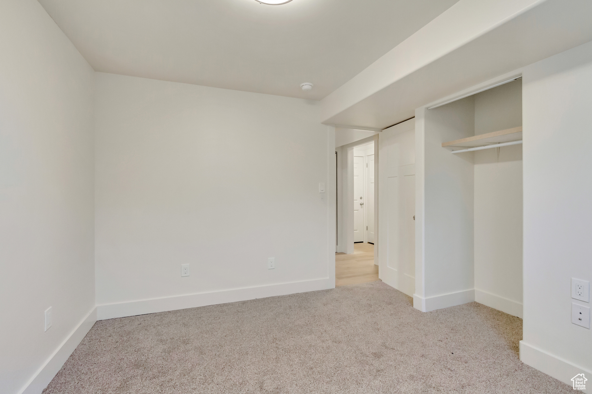 Unfurnished bedroom featuring light carpet and a closet