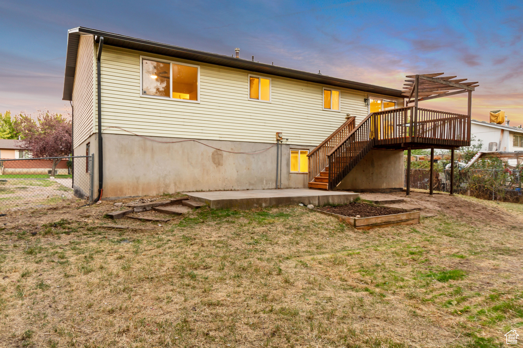 Back house at dusk featuring a yard and a wooden deck