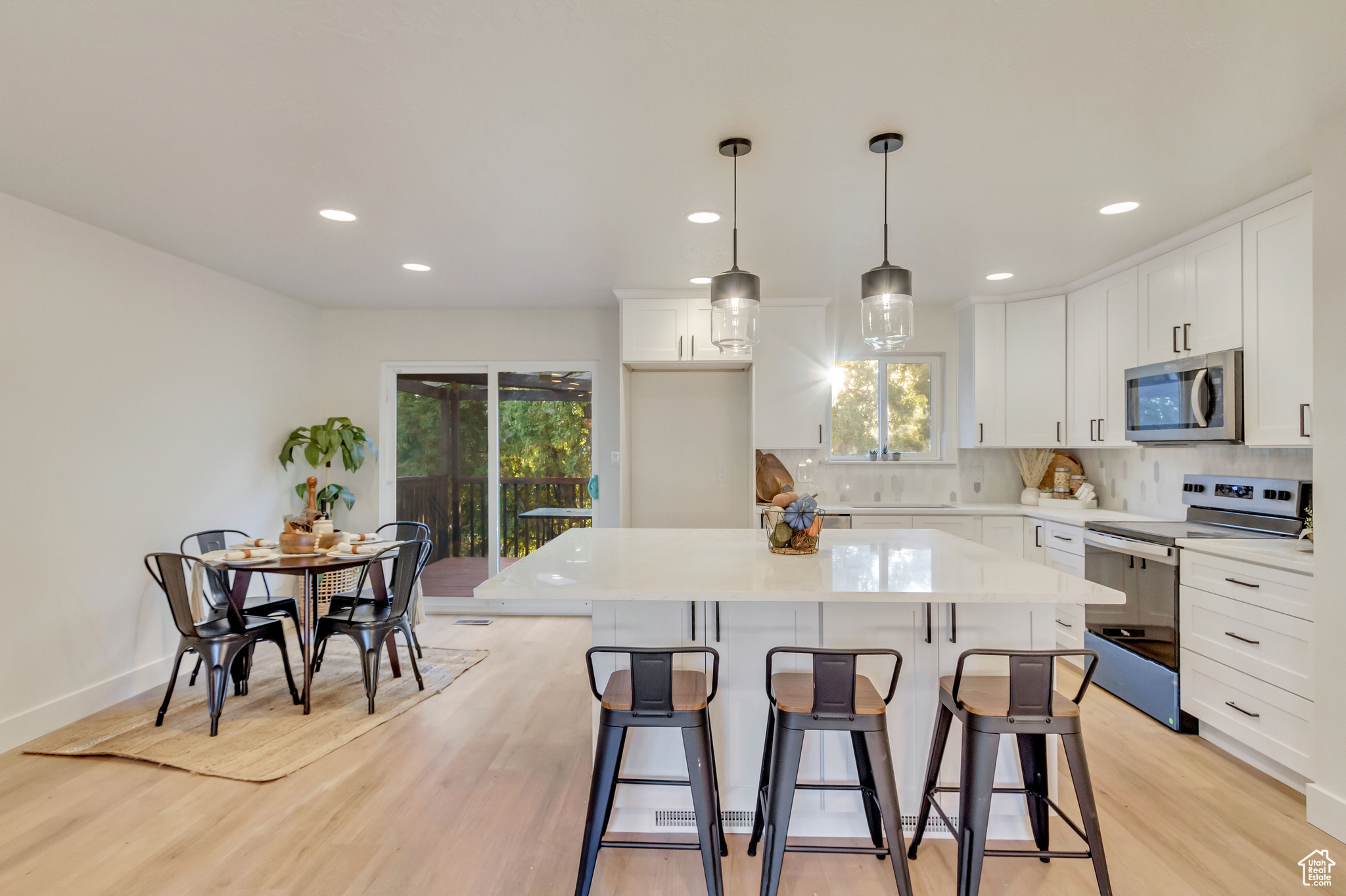 Kitchen with white cabinets, a center island, appliances with stainless steel finishes, and light wood-type flooring