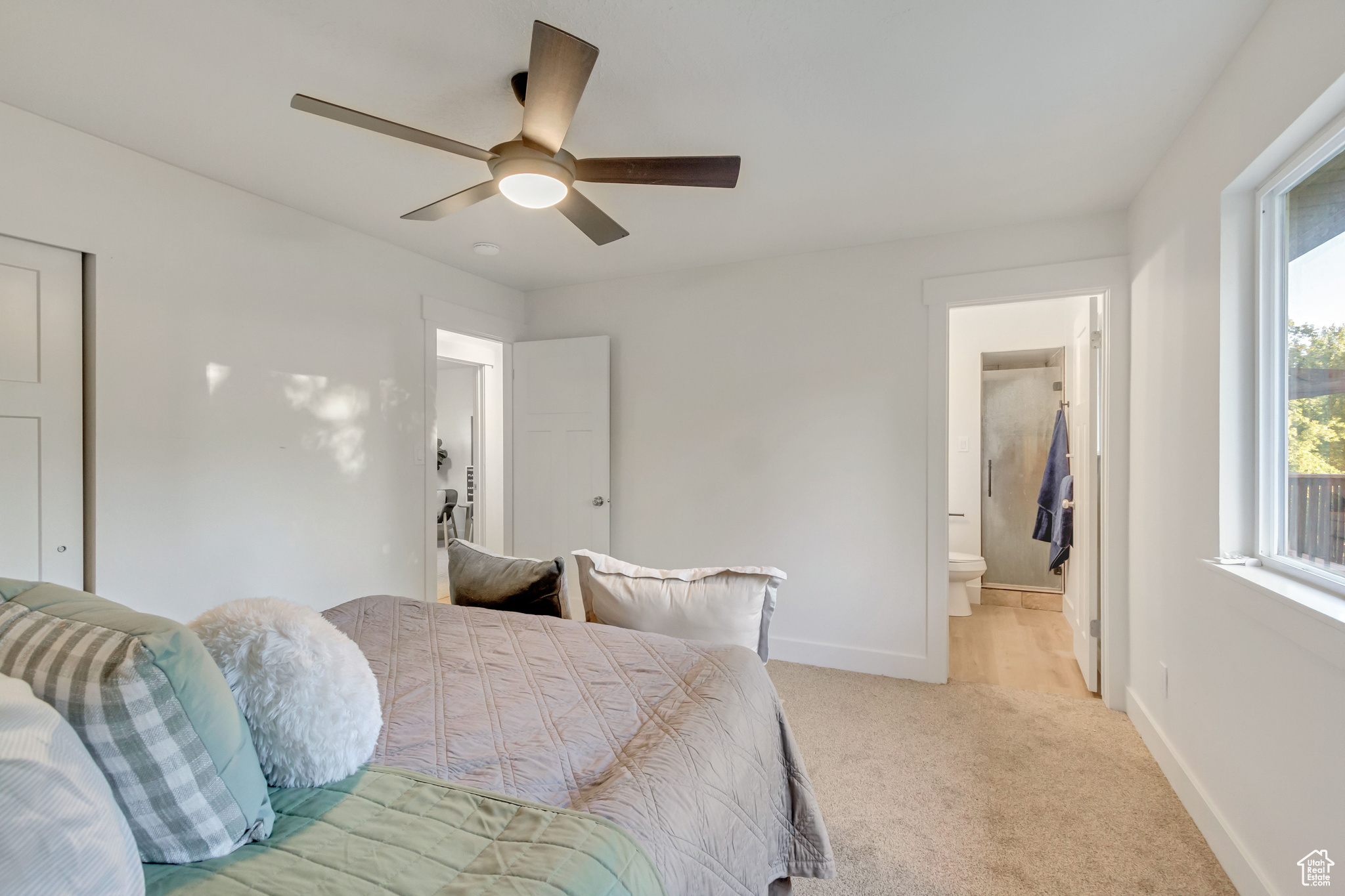 Carpeted bedroom with connected bathroom and ceiling fan