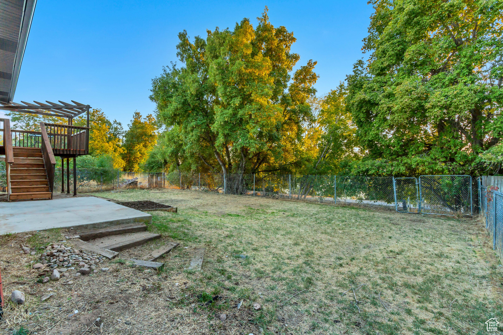 View of yard featuring a wooden deck, a pergola, and a patio area