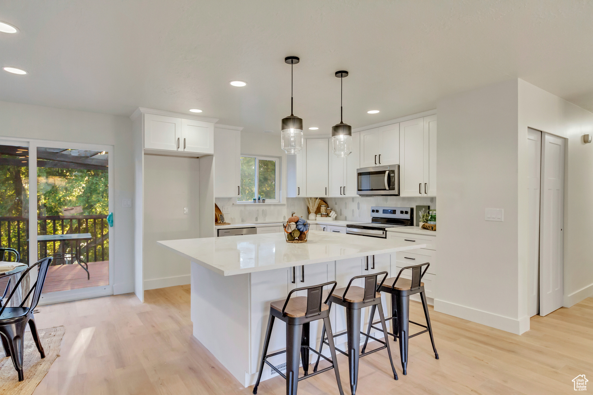 Kitchen with appliances with stainless steel finishes, white cabinetry, a kitchen island, and plenty of natural light