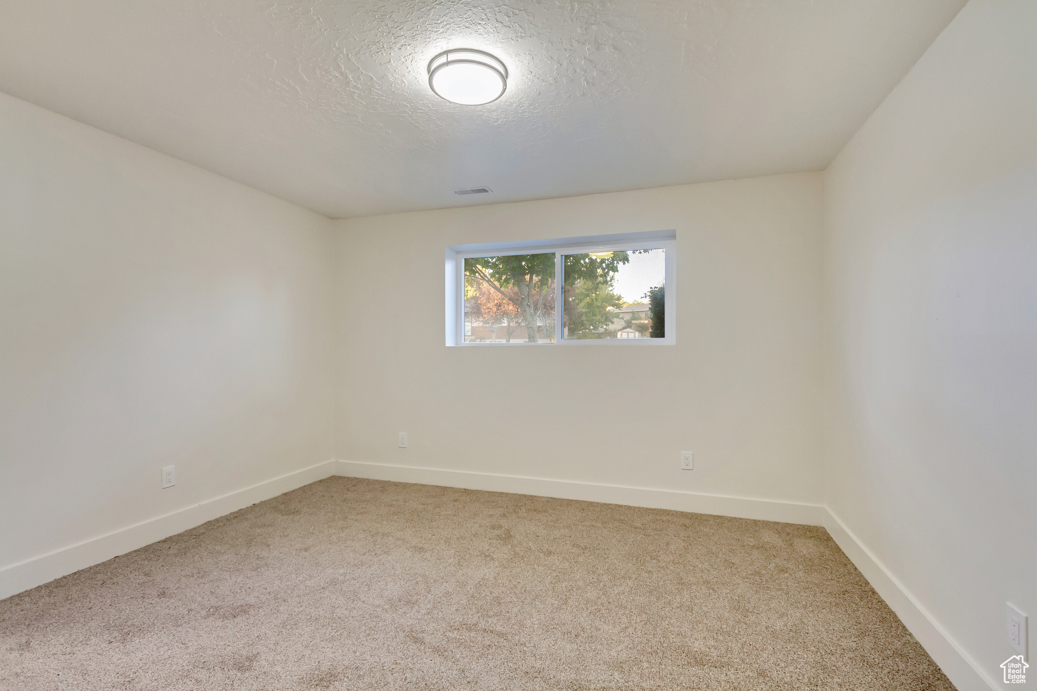 Carpeted spare room featuring a textured ceiling