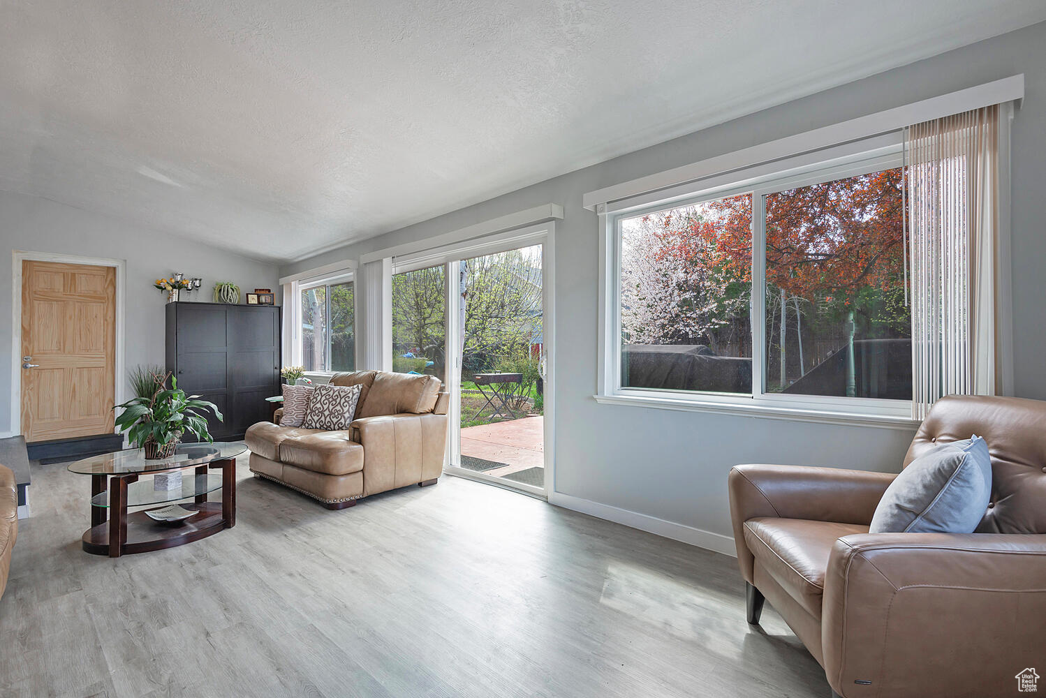 Living room with vaulted ceiling, a textured ceiling, and hardwood / wood-style flooring