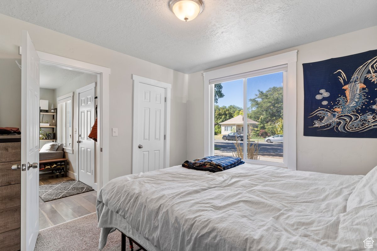 Bedroom with access to outside, a textured ceiling, and hardwood / wood-style floors