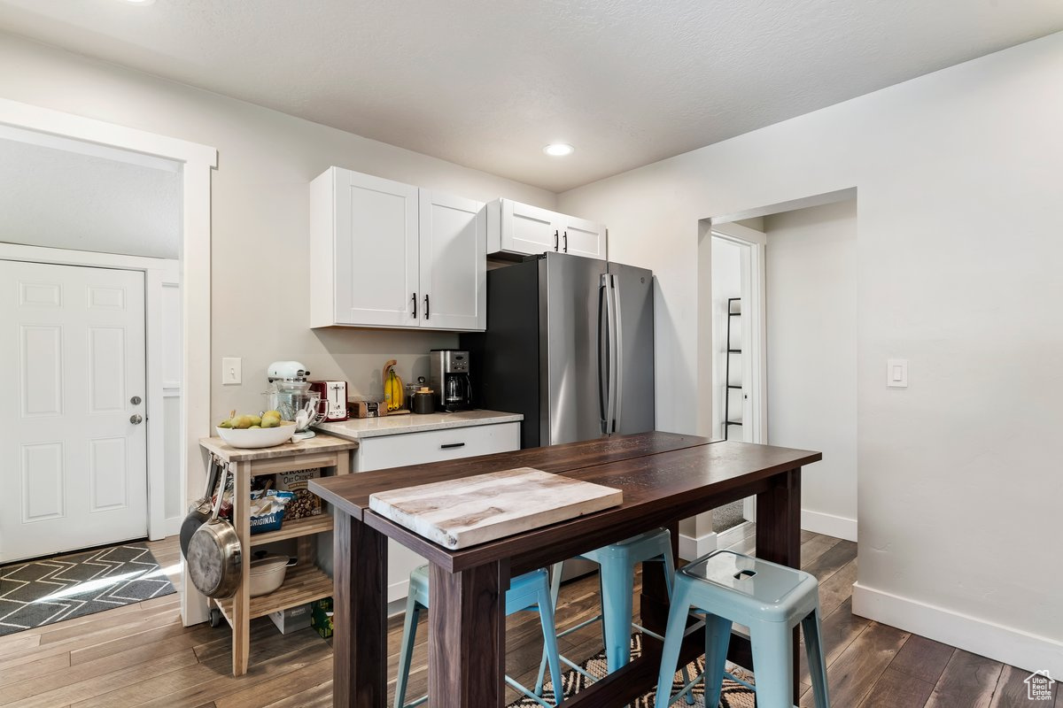 Kitchen with stainless steel fridge, white cabinetry, and dark hardwood / wood-style flooring