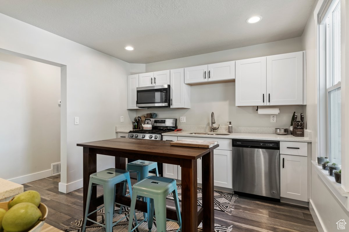 Kitchen featuring white cabinets, appliances with stainless steel finishes, a healthy amount of sunlight, and sink