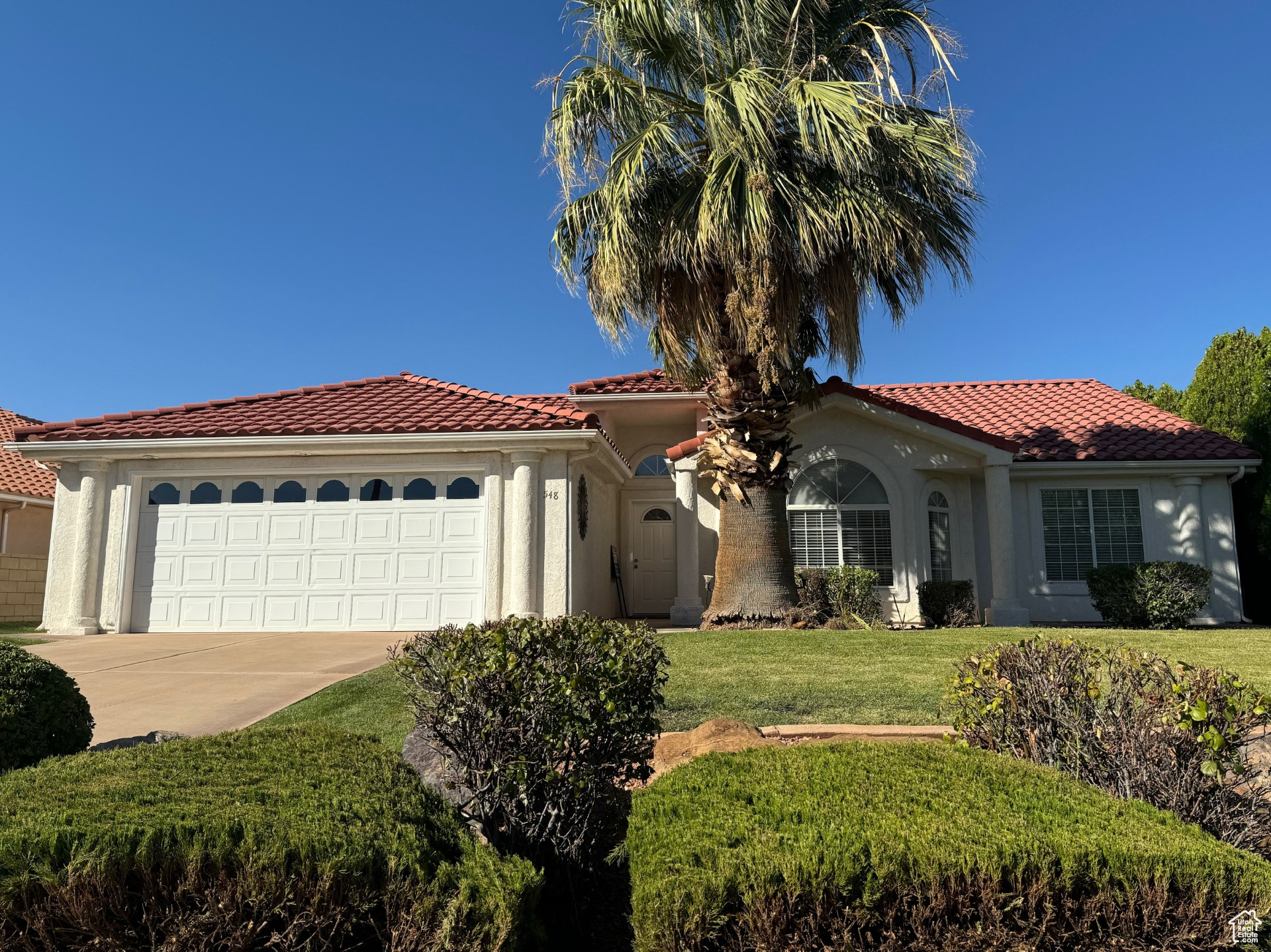 Mediterranean / spanish home featuring a garage and a front lawn