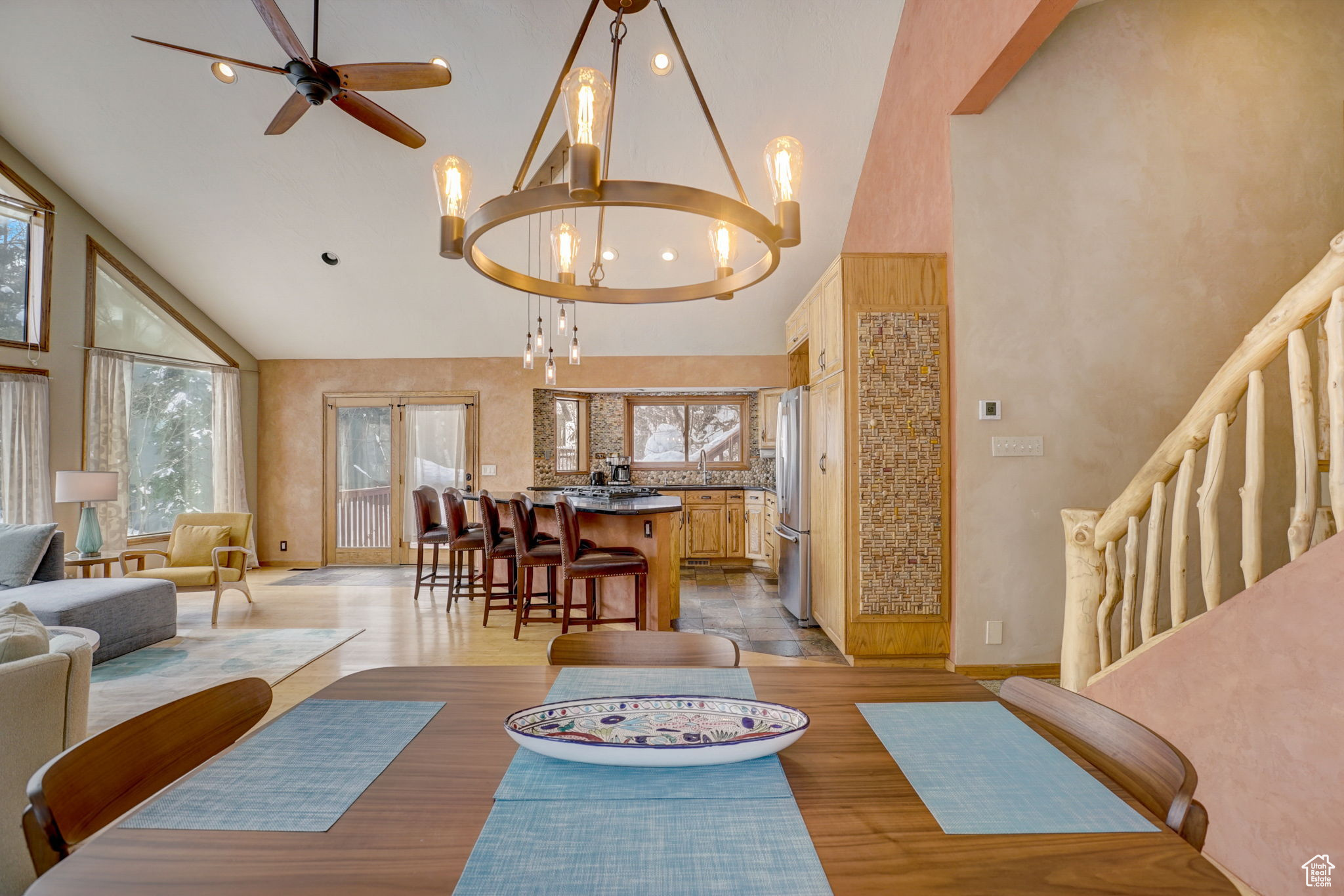 Dining room featuring high vaulted ceiling, light hardwood / wood-style floors, and ceiling fan with notable chandelier