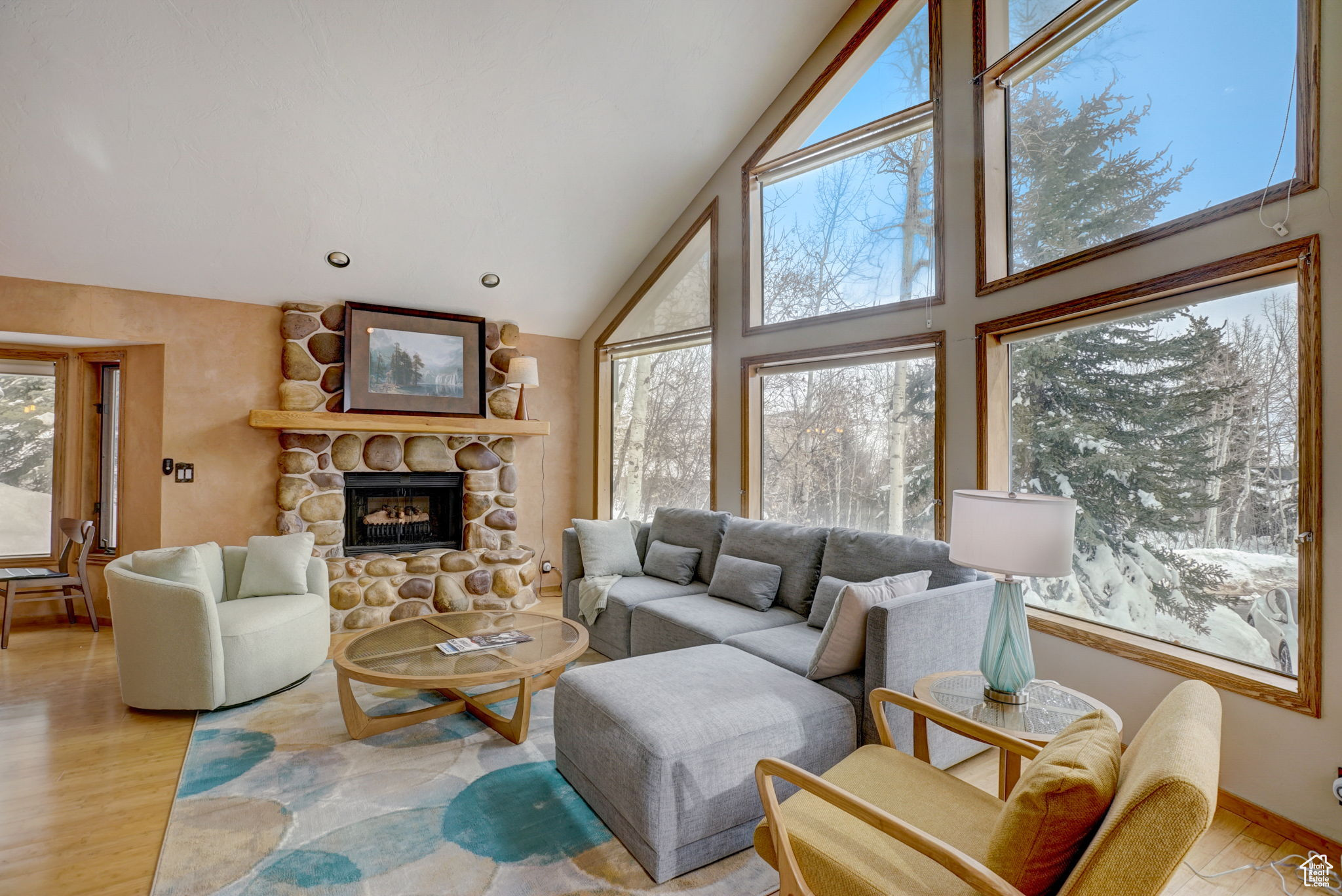 Living room featuring a stone fireplace, light hardwood / wood-style flooring, and high vaulted ceiling