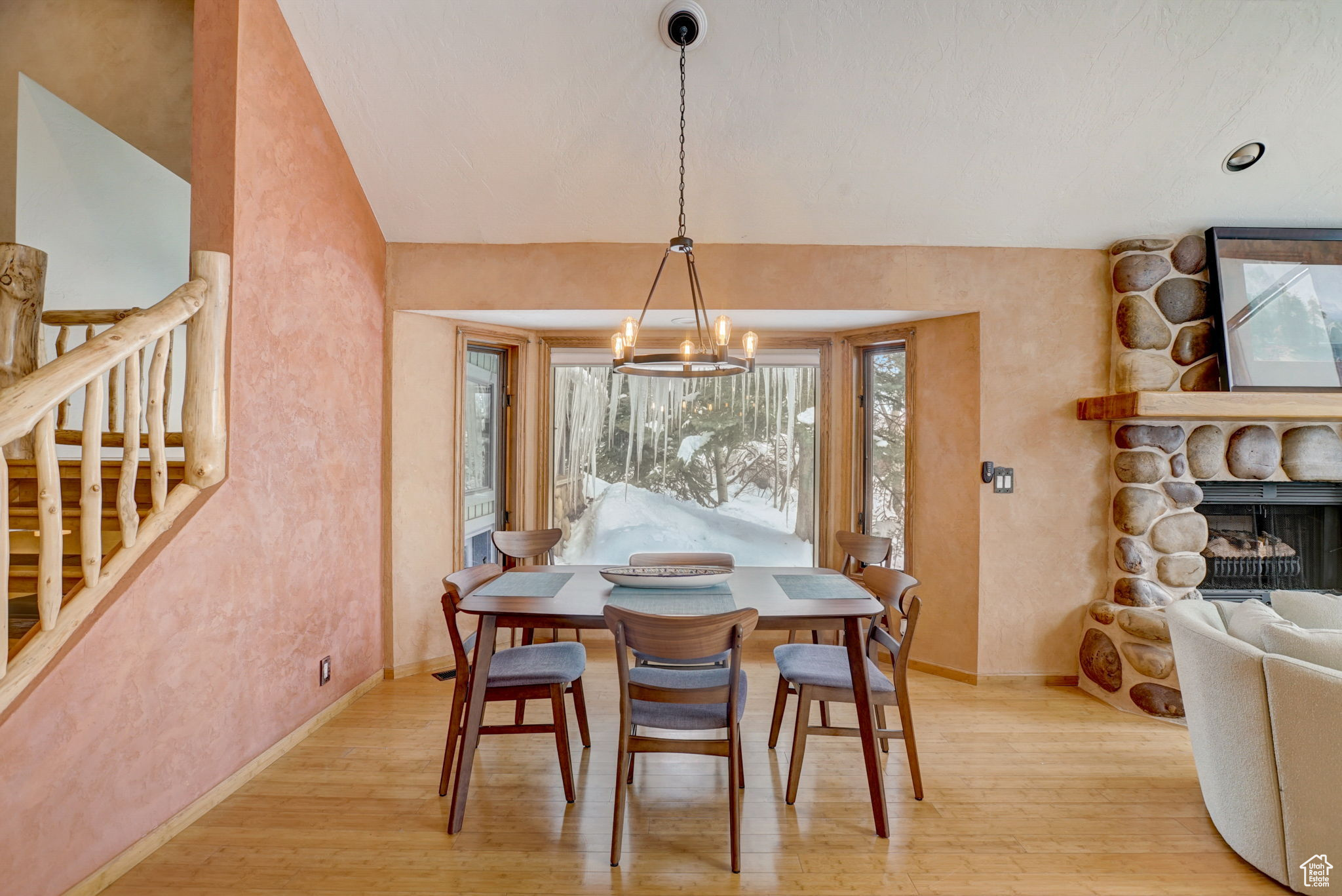 Dining room with light wood-type flooring, a fireplace, an inviting chandelier, and plenty of natural light