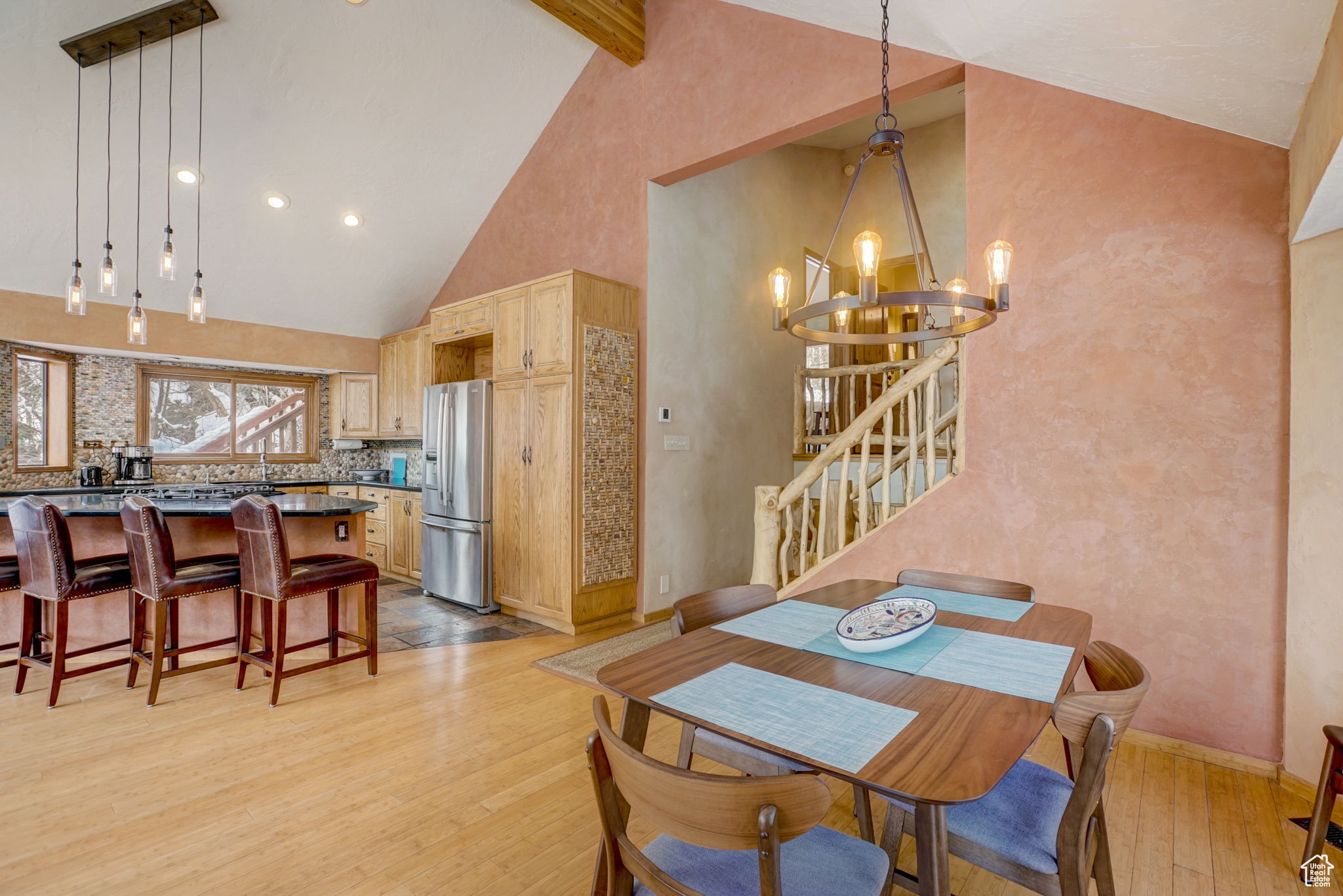 Dining area with high vaulted ceiling, beam ceiling, light hardwood / wood-style flooring, and a notable chandelier