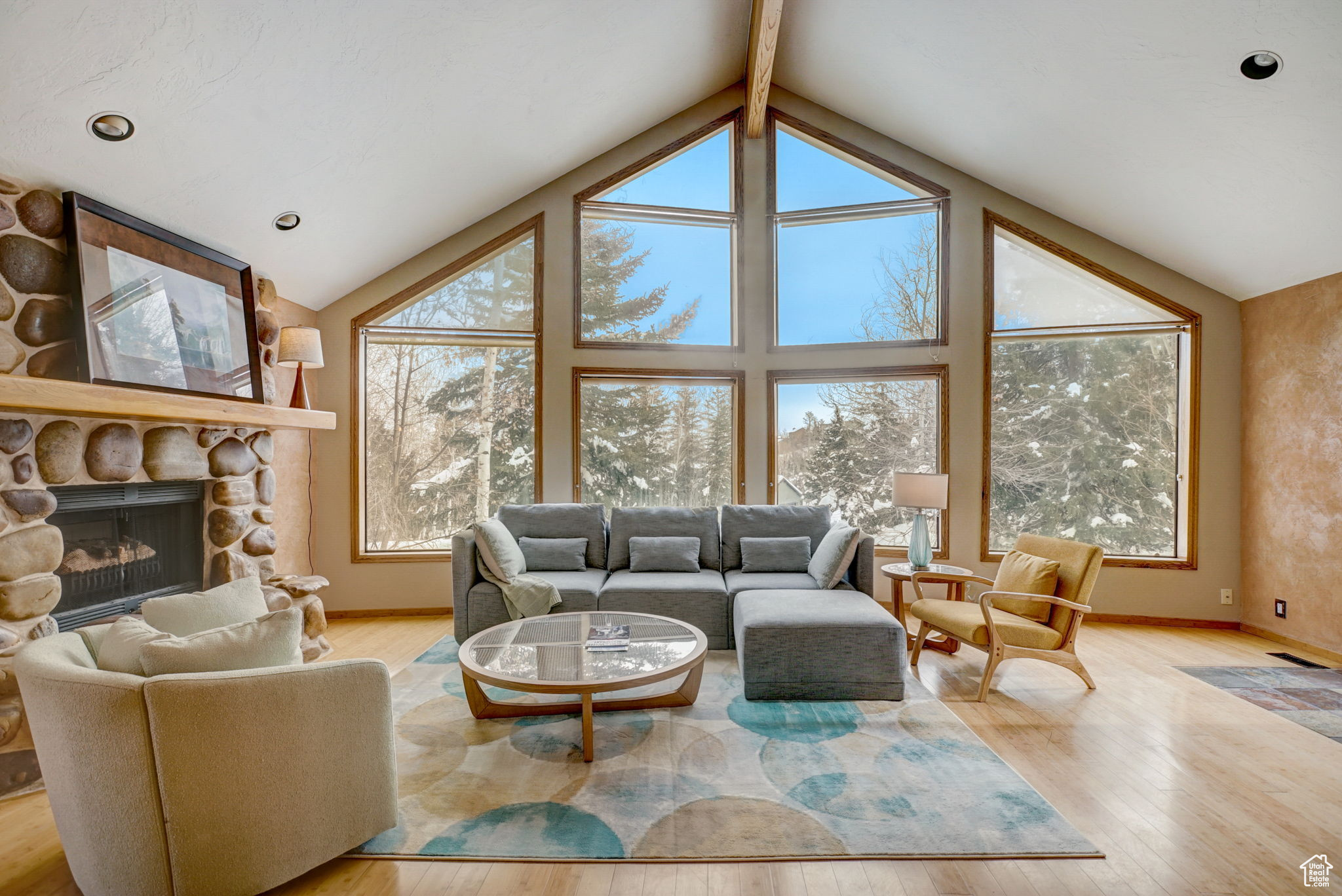 Living room featuring light hardwood / wood-style flooring, beam ceiling, high vaulted ceiling, and a fireplace