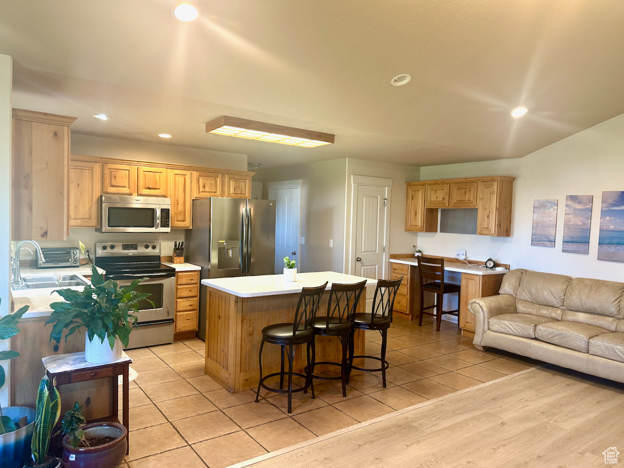 Kitchen with sink, a kitchen island, stainless steel appliances, a breakfast bar area, and light wood-type flooring