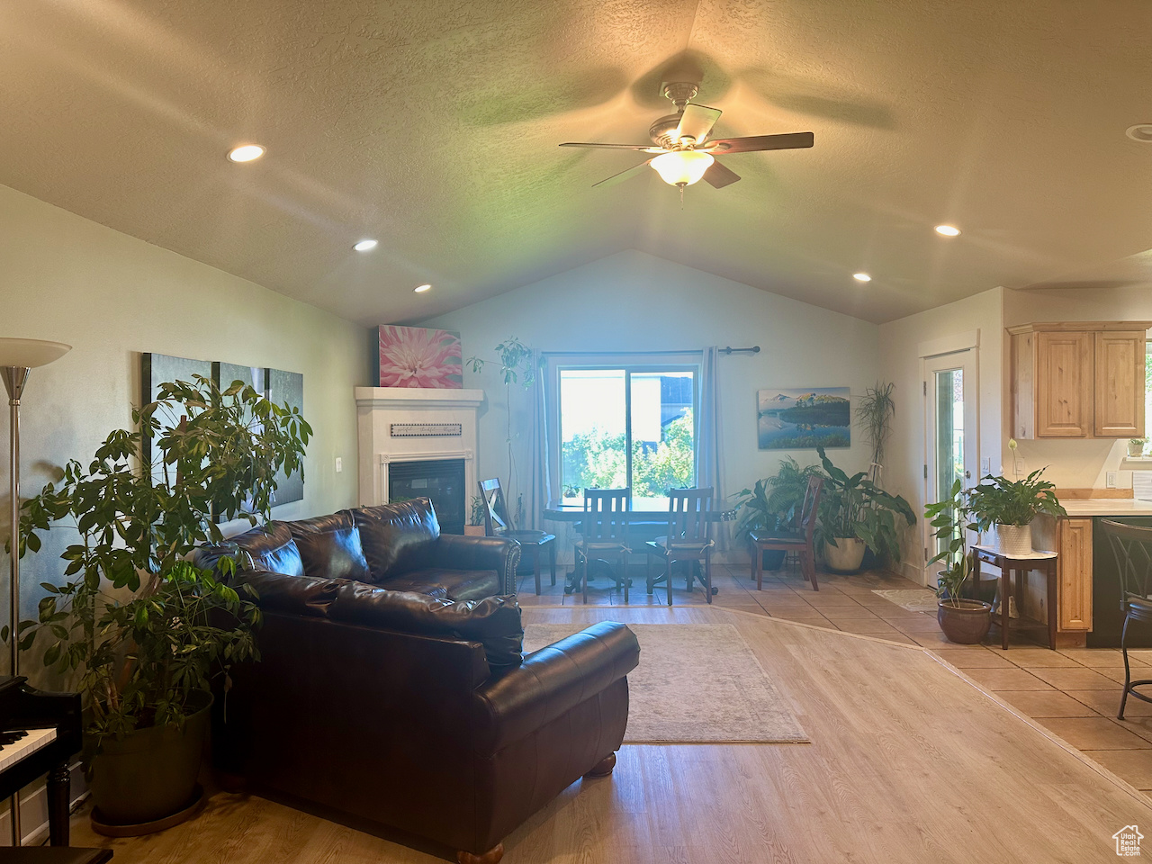 Living room with ceiling fan, a textured ceiling, light hardwood / wood-style flooring, and lofted ceiling