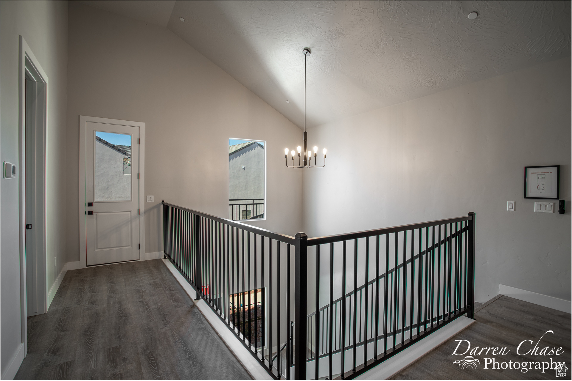 Hall featuring high vaulted ceiling, a chandelier, a textured ceiling, and dark hardwood / wood-style flooring