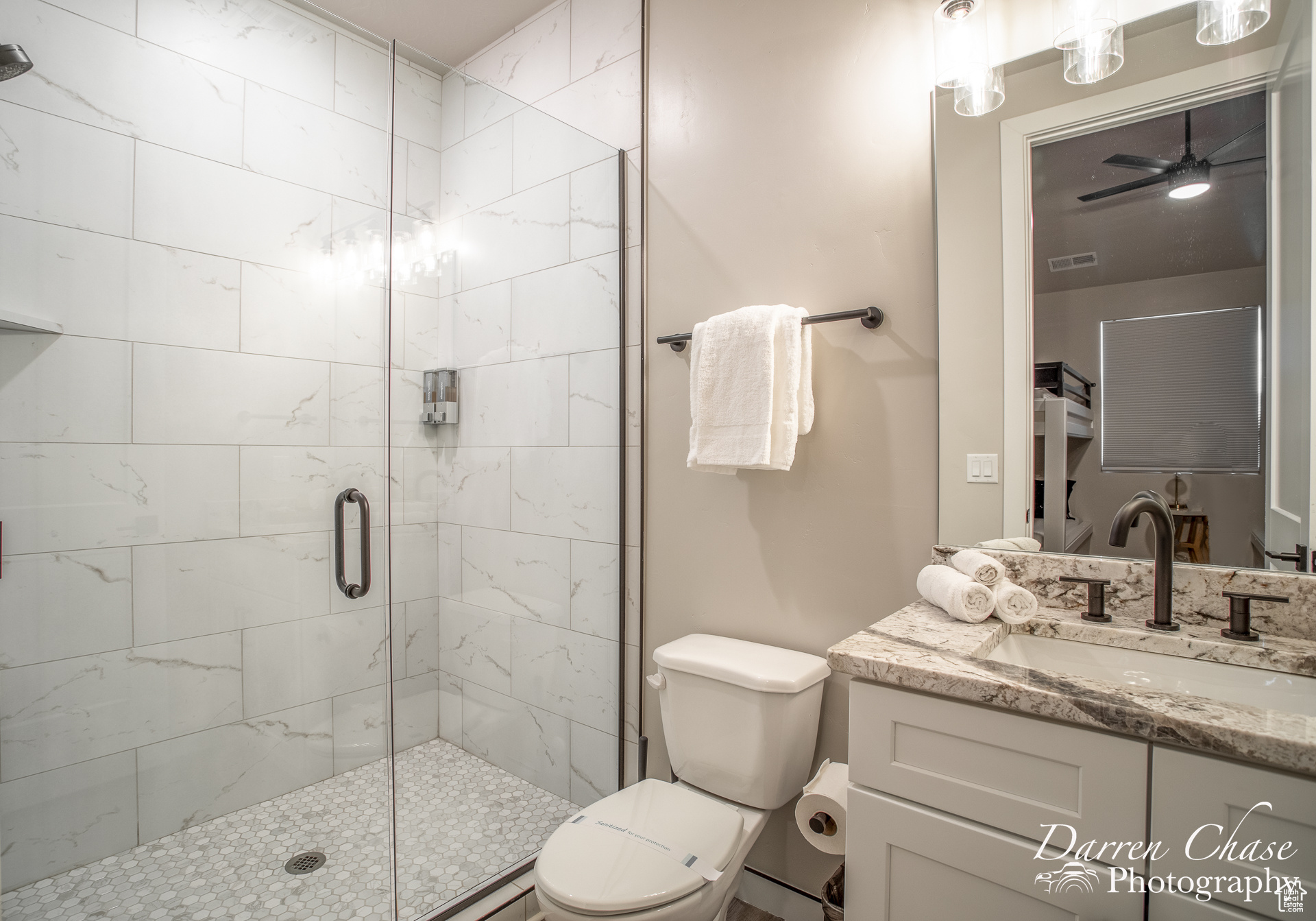 Bathroom with vanity, toilet, ceiling fan, and a shower with shower door