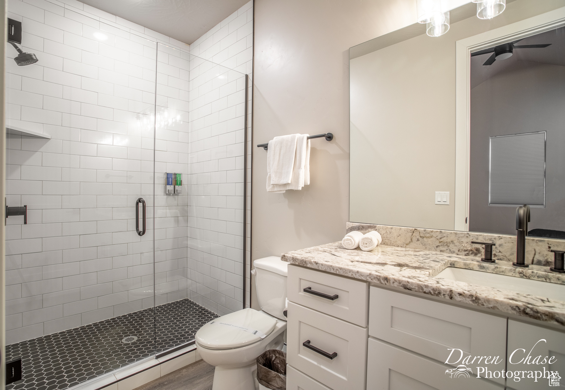 Bathroom featuring wood-type flooring, vanity, toilet, and an enclosed shower