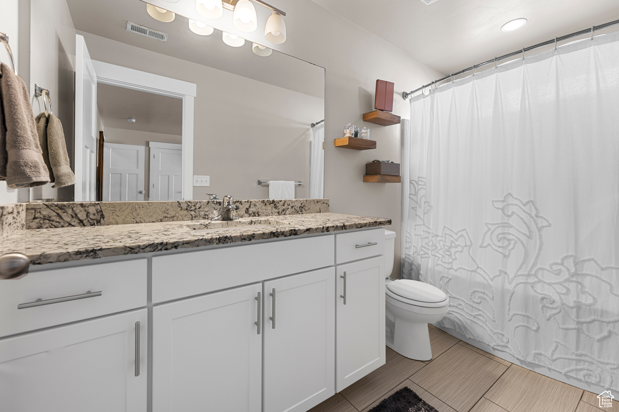 Bathroom with curtained shower, vanity, and toilet