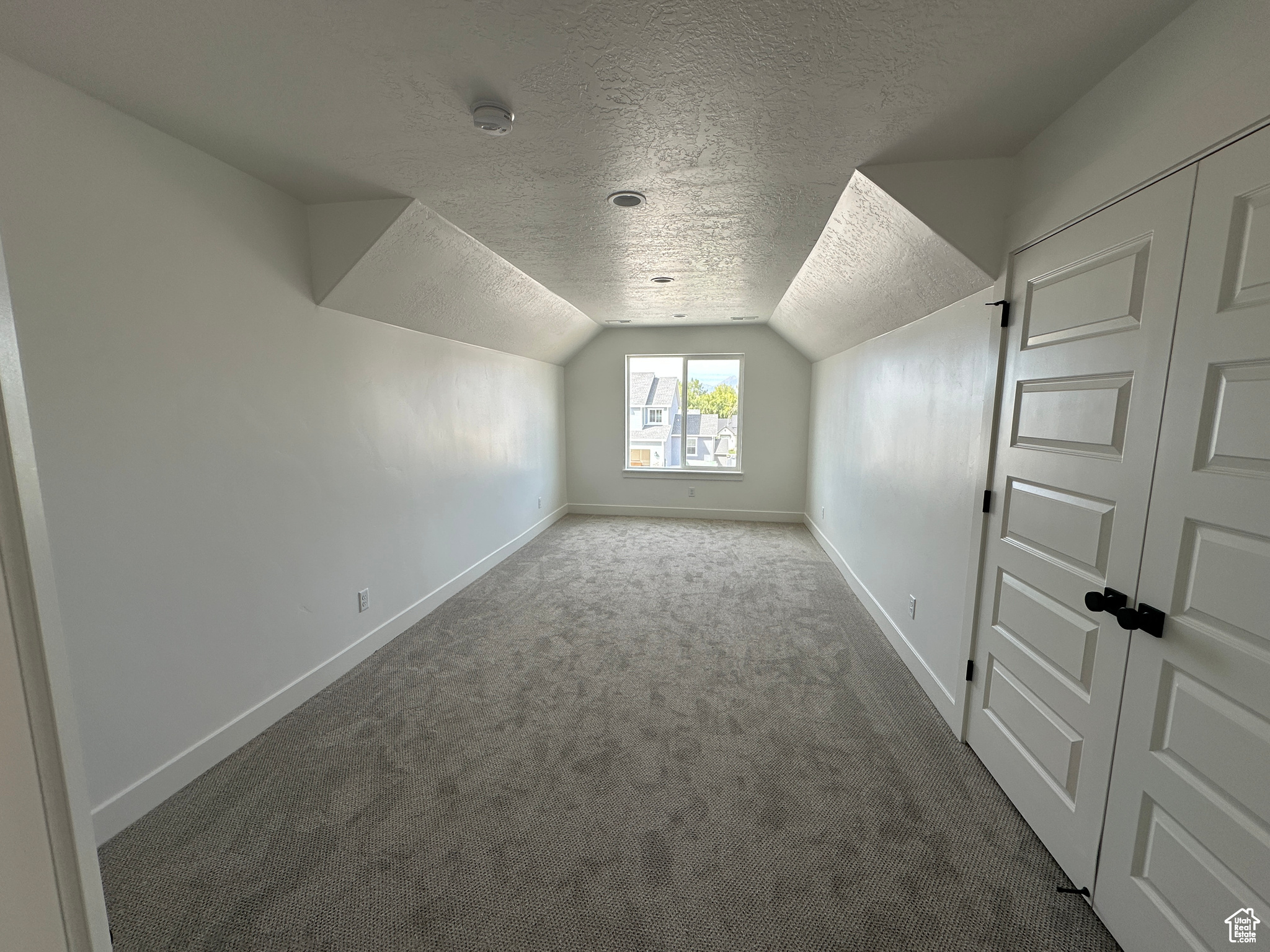 Bonus room with vaulted ceiling, a textured ceiling, and carpet flooring