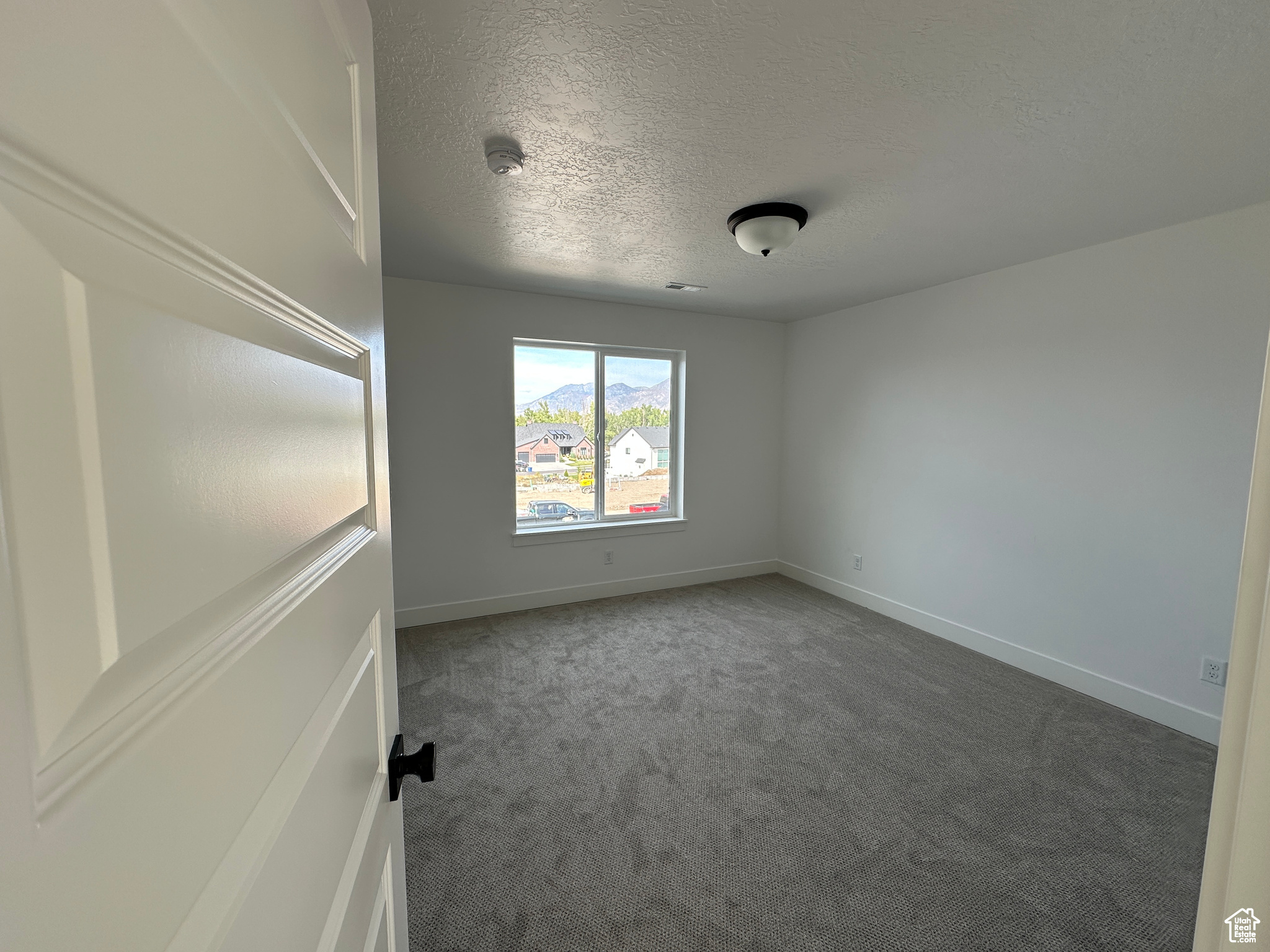 Empty room with carpet and a textured ceiling