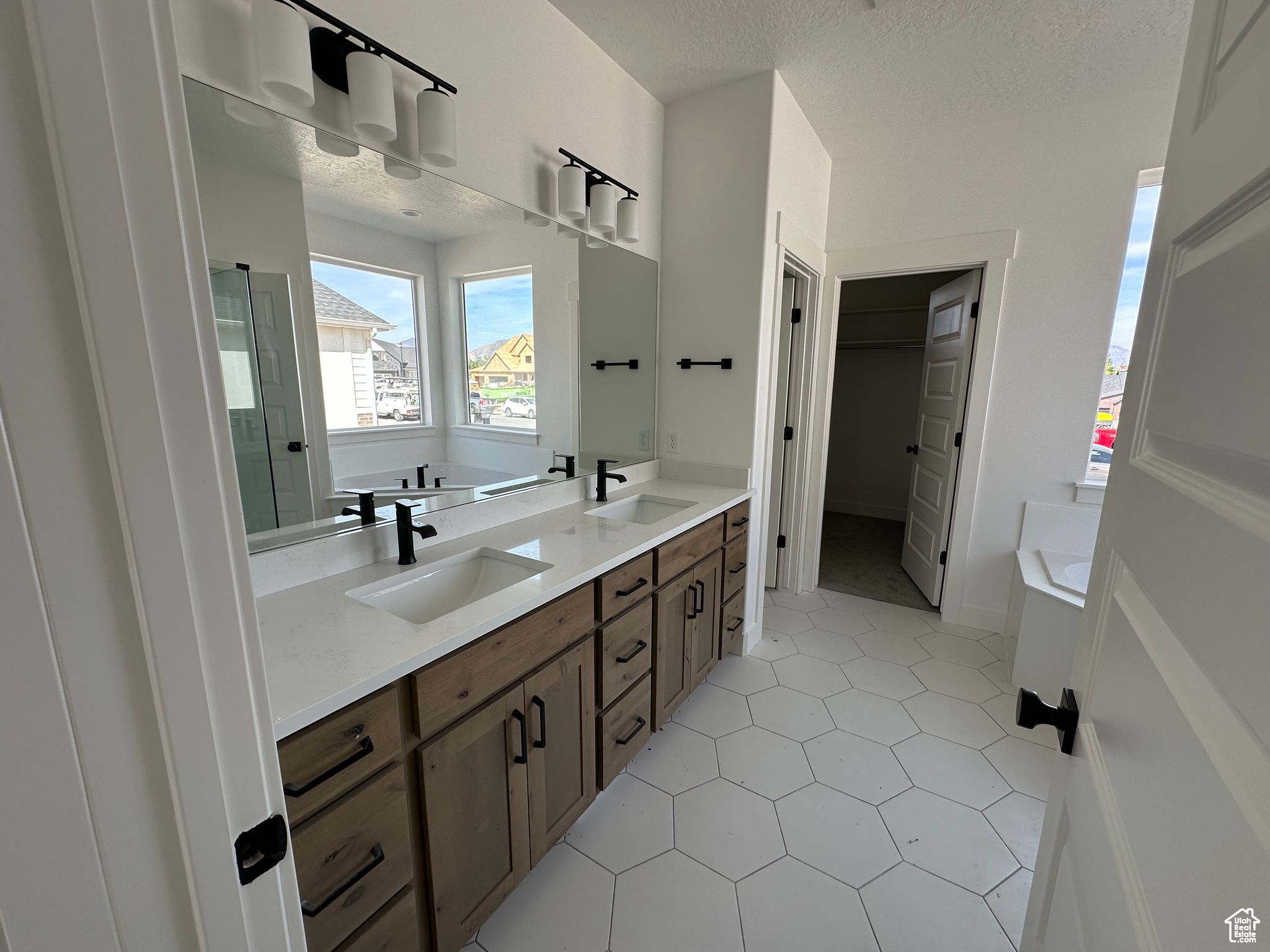 Bathroom featuring tile patterned floors, dual vanity, a textured ceiling, vanity, and separate shower and tub