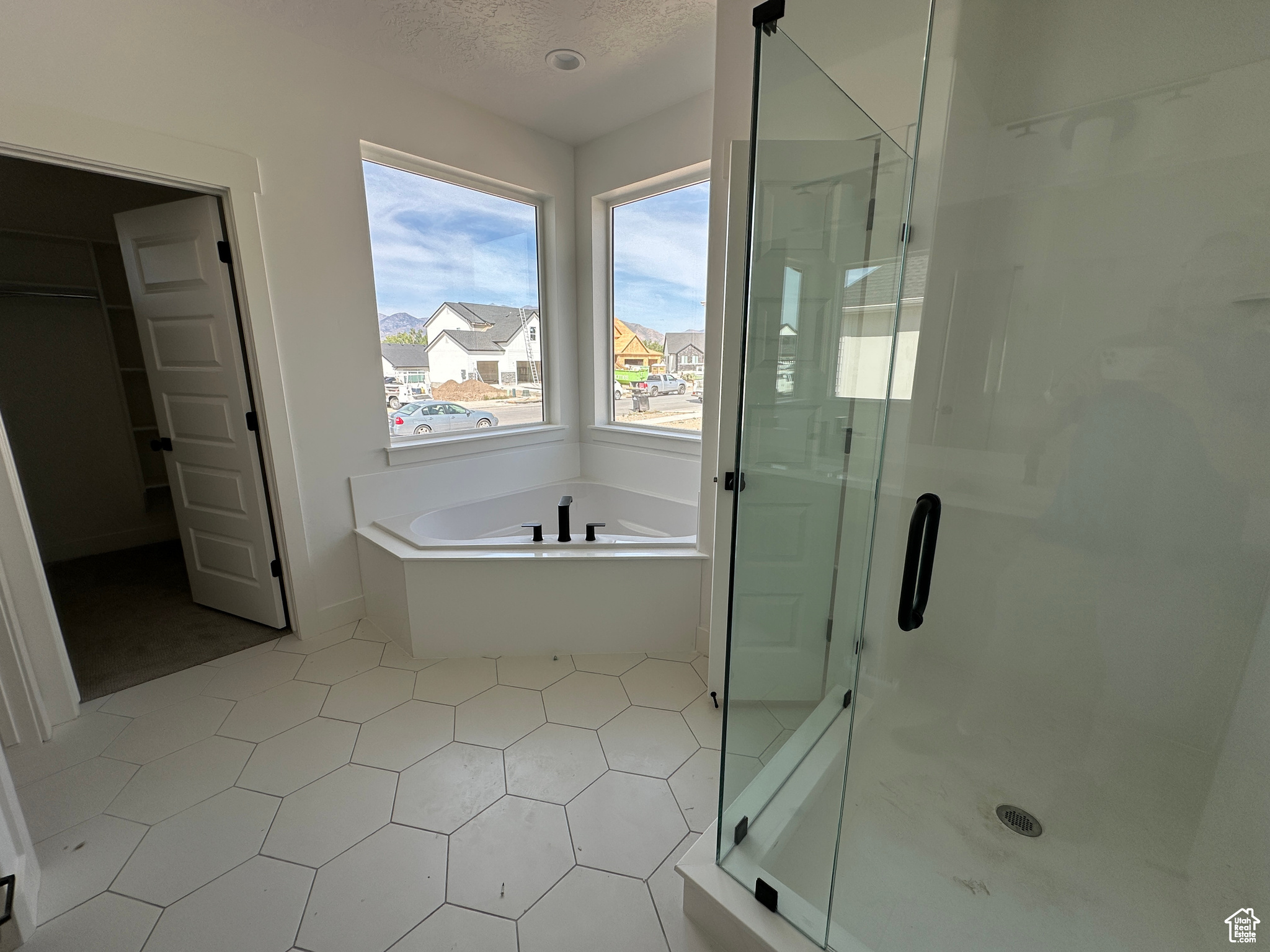 Bathroom featuring separate shower and tub, tile patterned flooring, and a textured ceiling