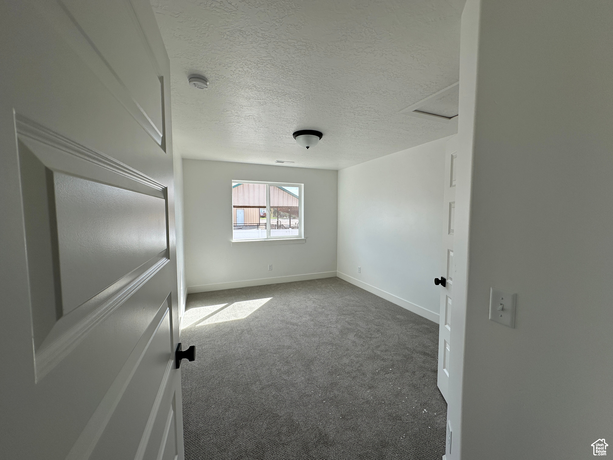 Empty room with a textured ceiling and carpet