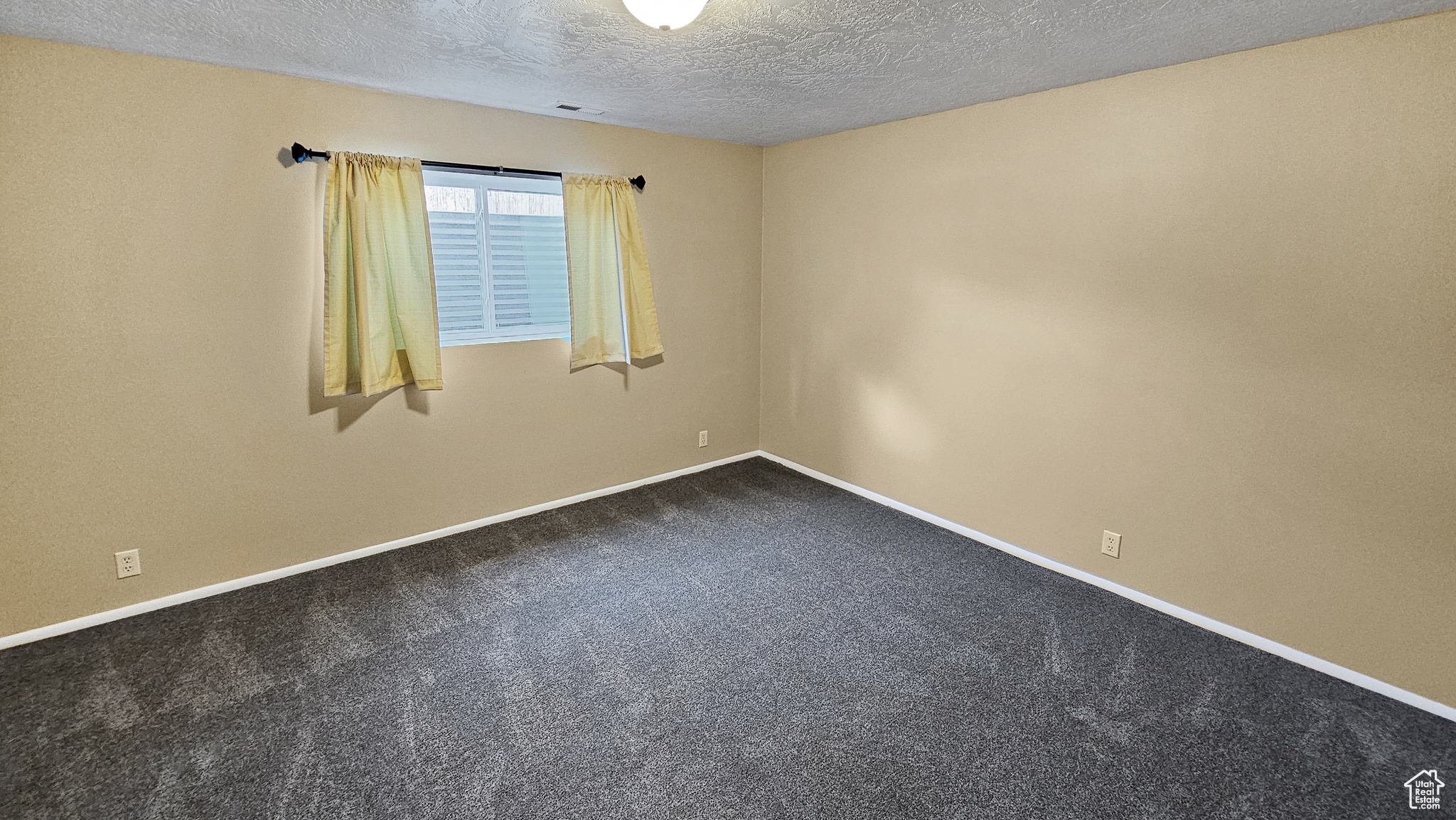 Spare room featuring a textured ceiling and carpet flooring