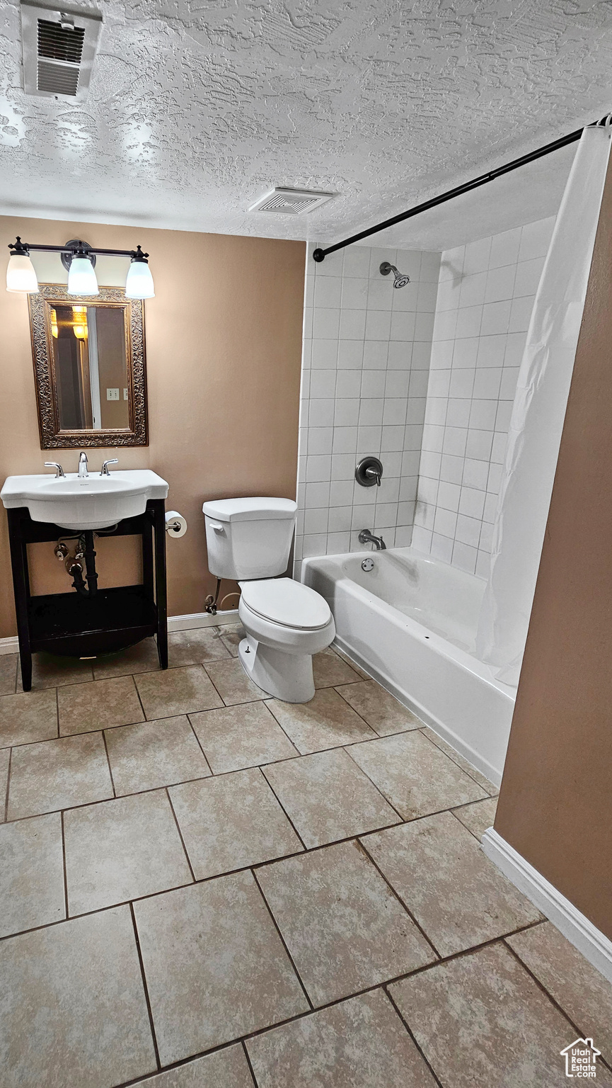 Full bathroom featuring vanity, tile patterned flooring, a textured ceiling, shower / tub combo, and toilet