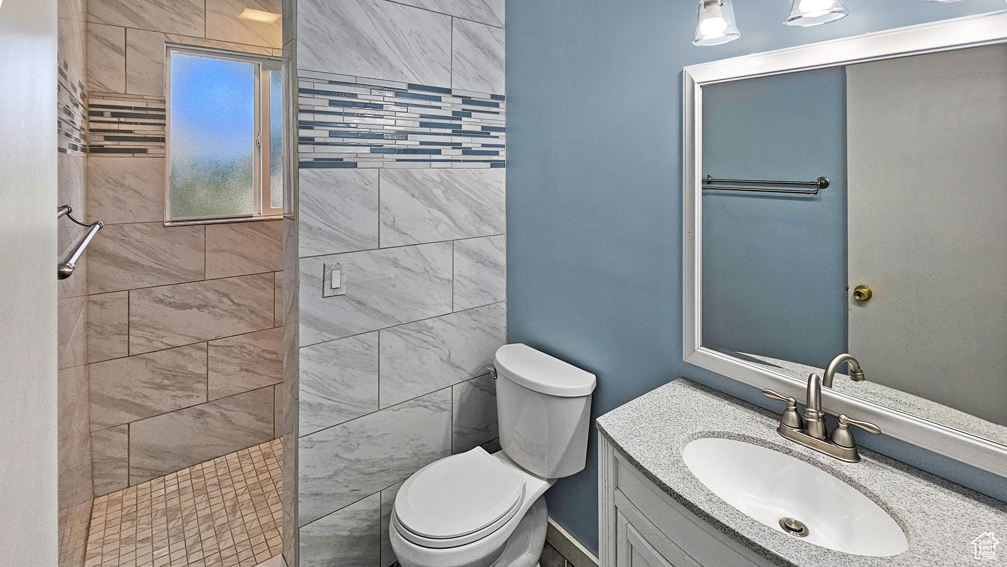 Bathroom with a tile shower, vanity, and toilet