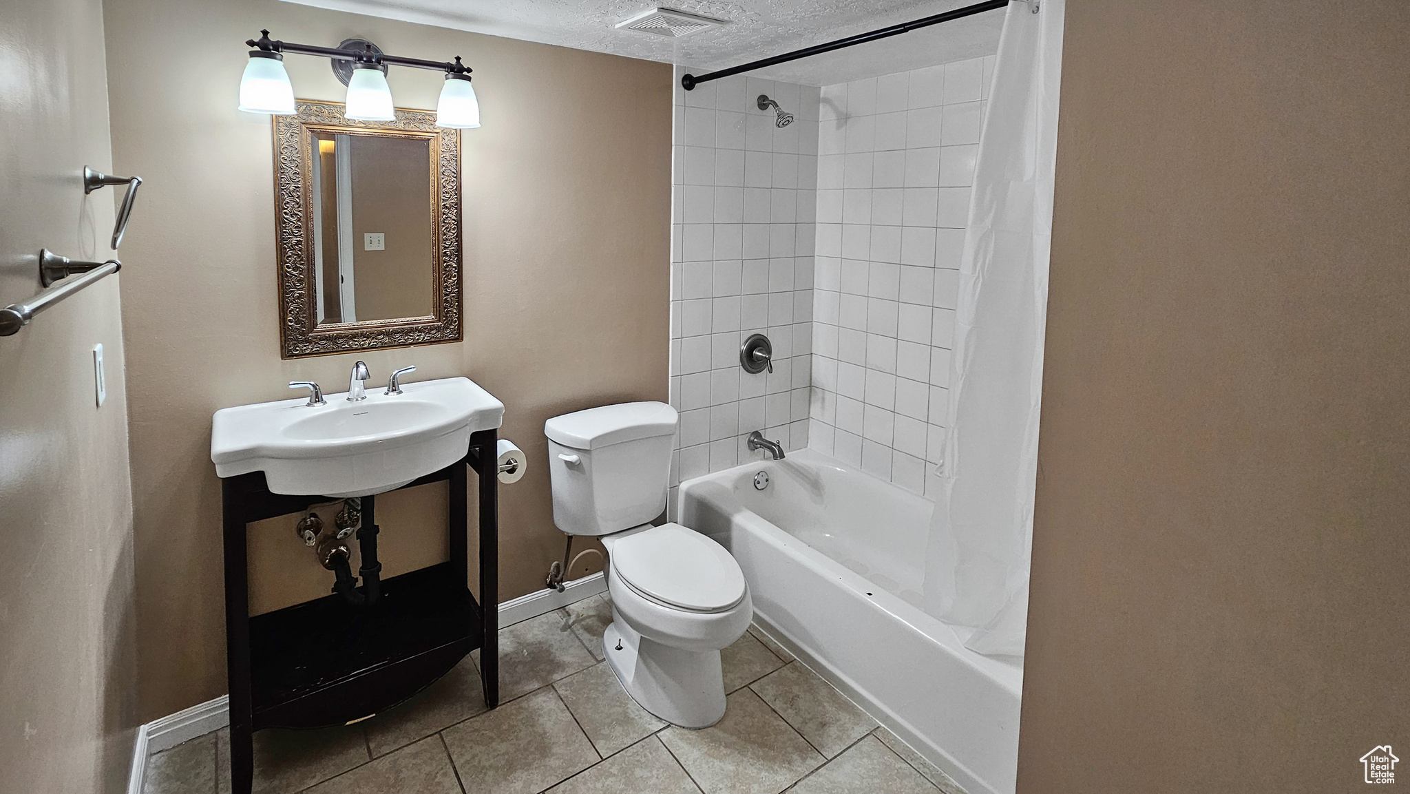 Bathroom with shower / bath combo, a textured ceiling, tile patterned floors, and toilet